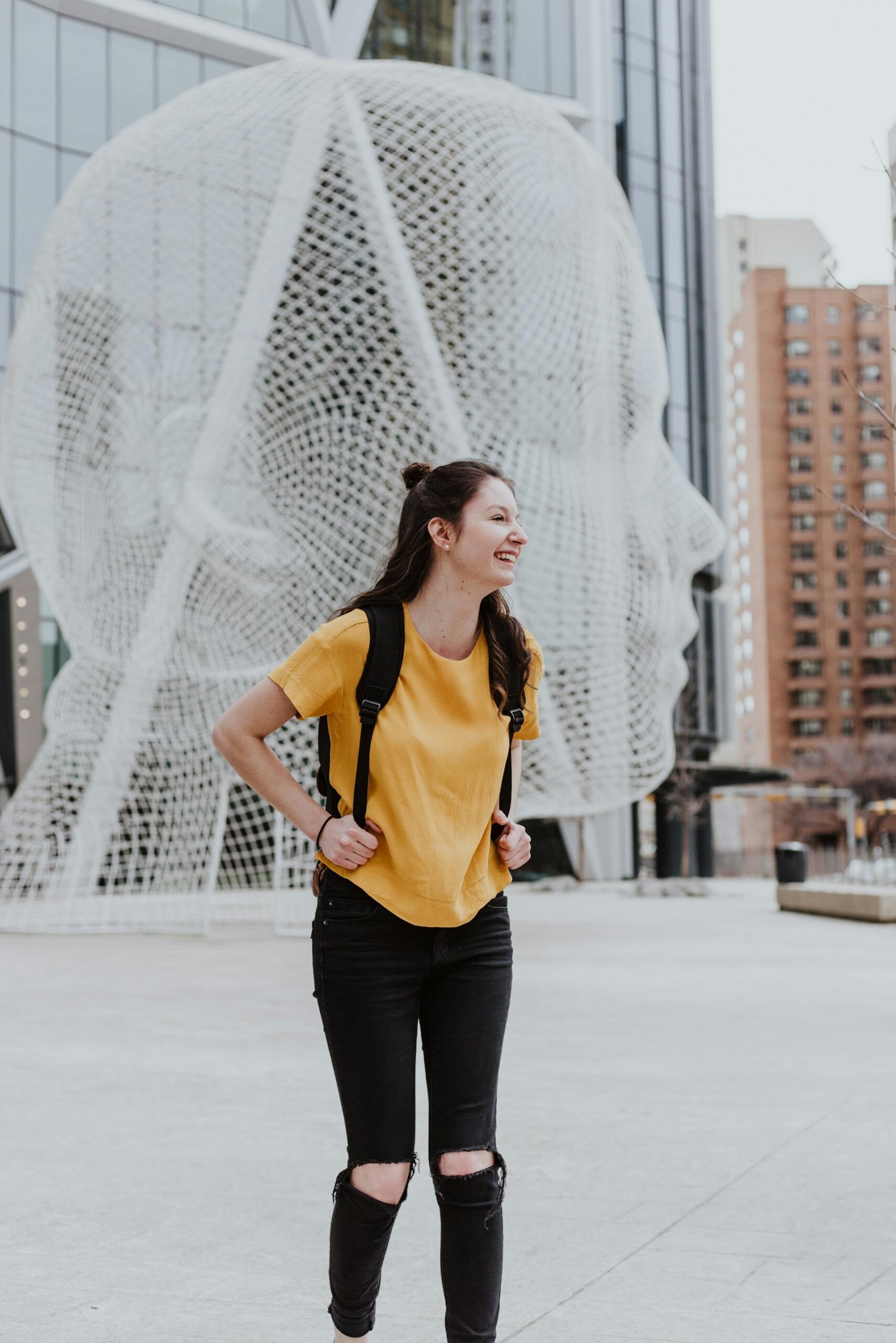 A person wearing yellow and black in front of a sculpture.