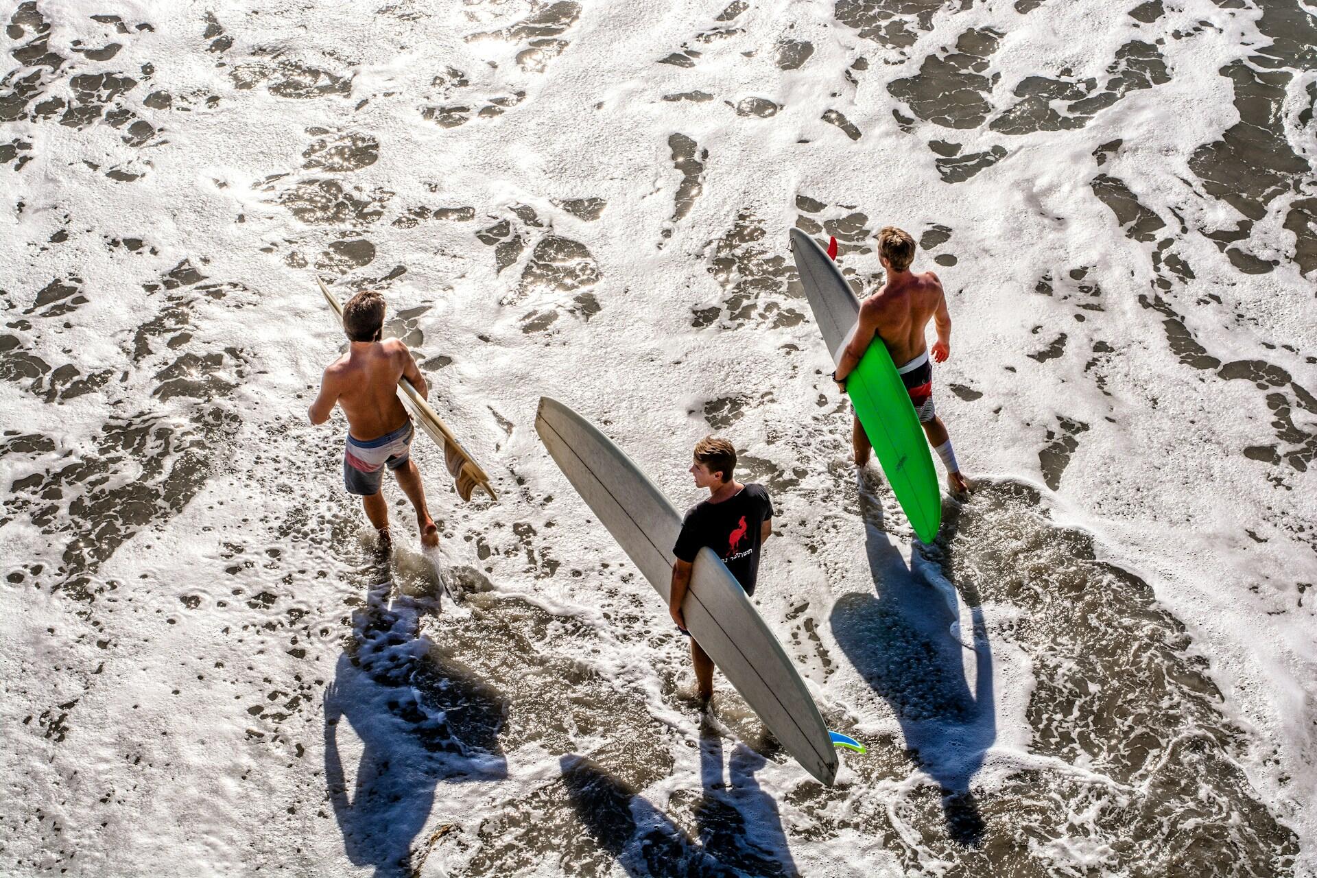 Surfers standing on a beach with their boards.