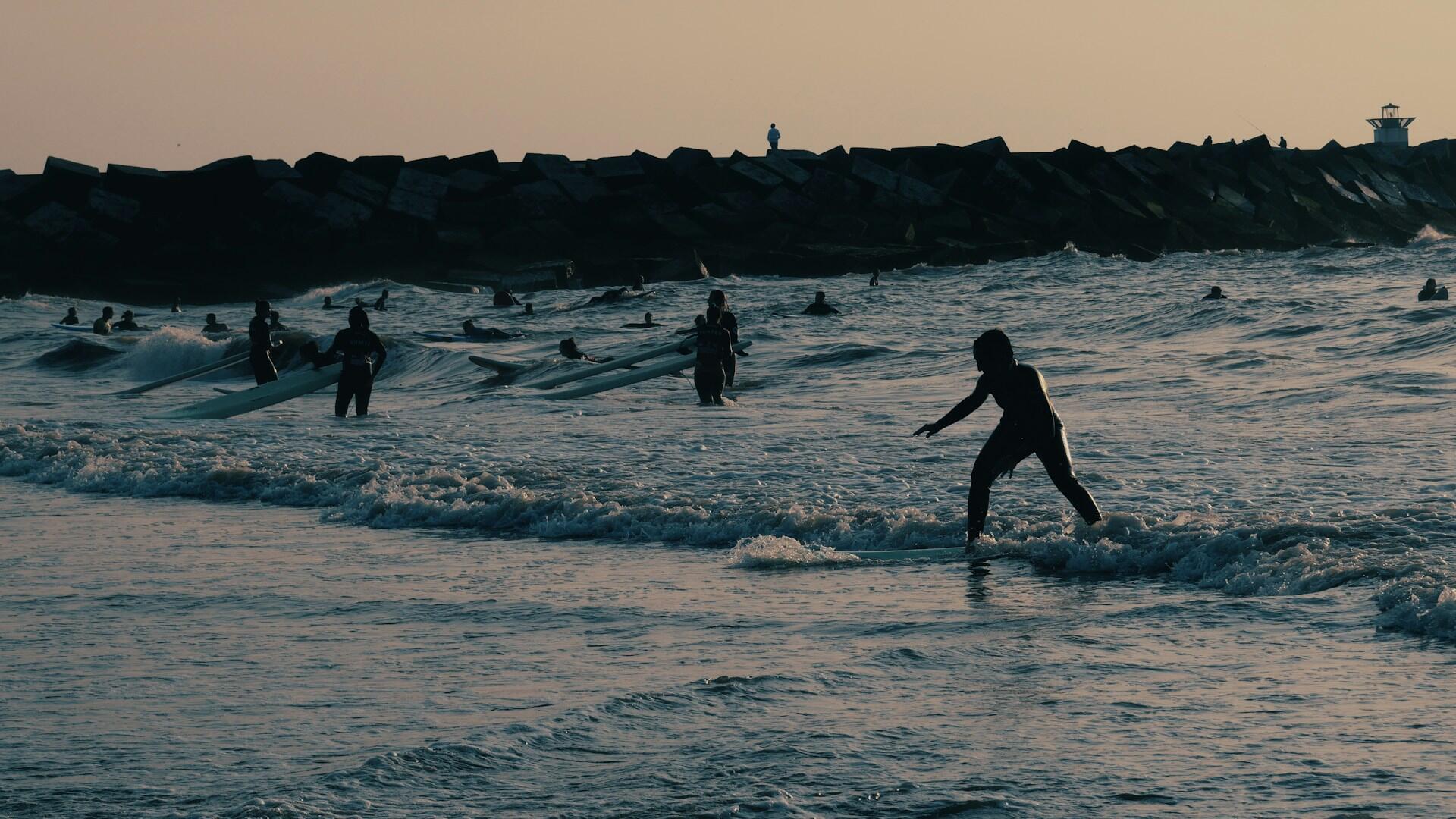 Surfers gliding to shore at sunset.