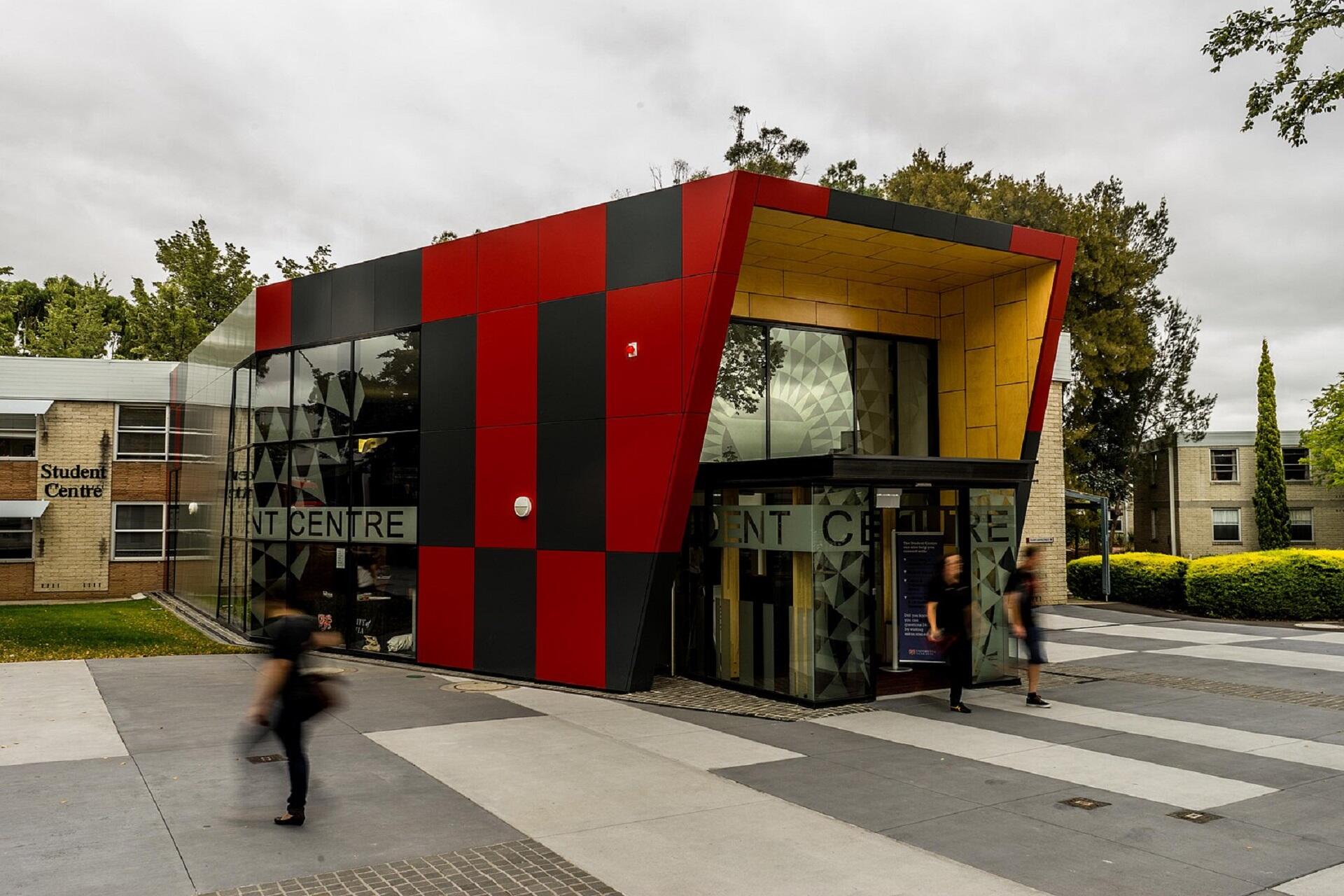 A small red and black building on a cloudy day.