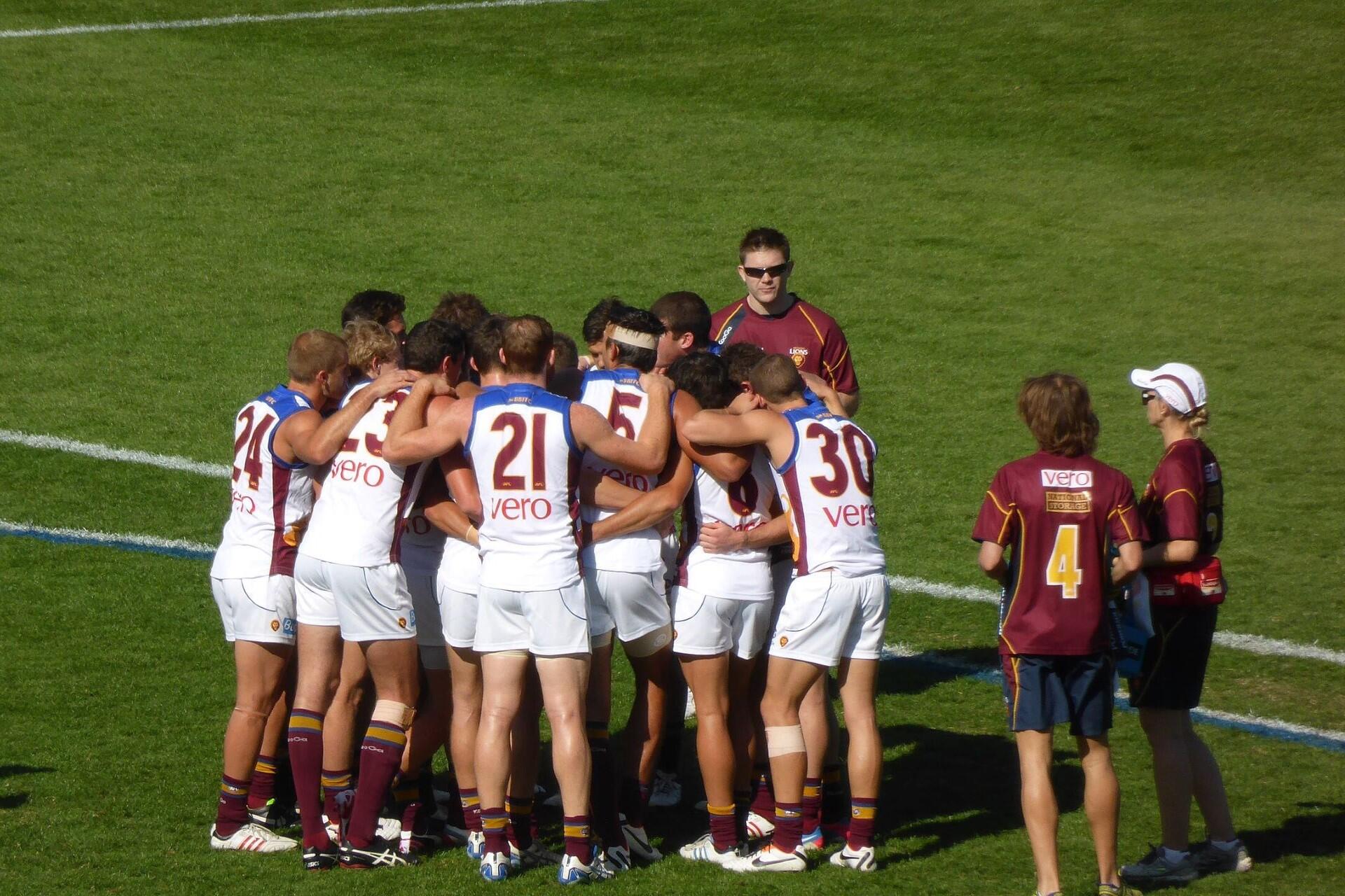 The Brisbane AFL team in a huddle.