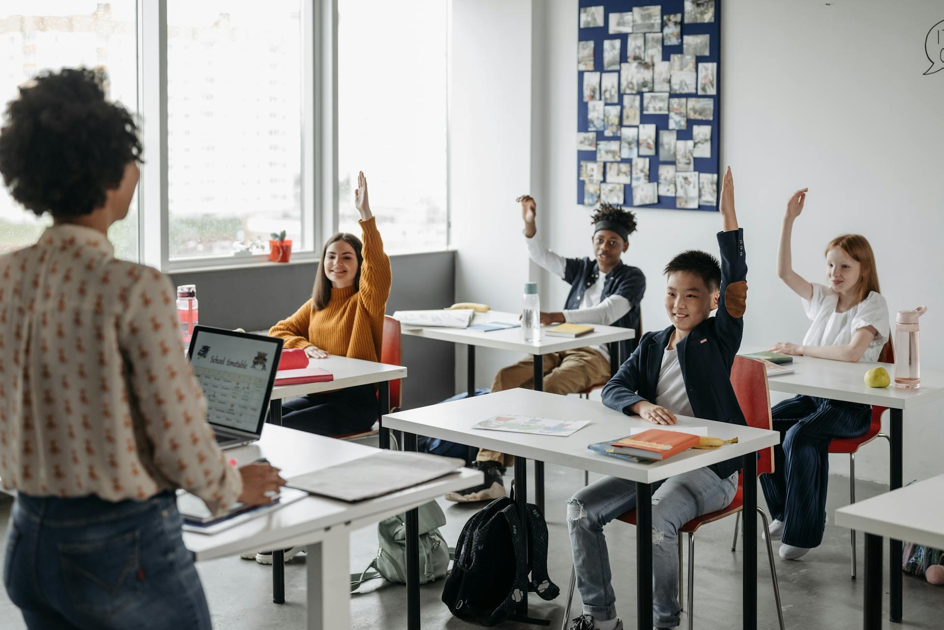 a classroom of engaged students all raising their hands and smiling