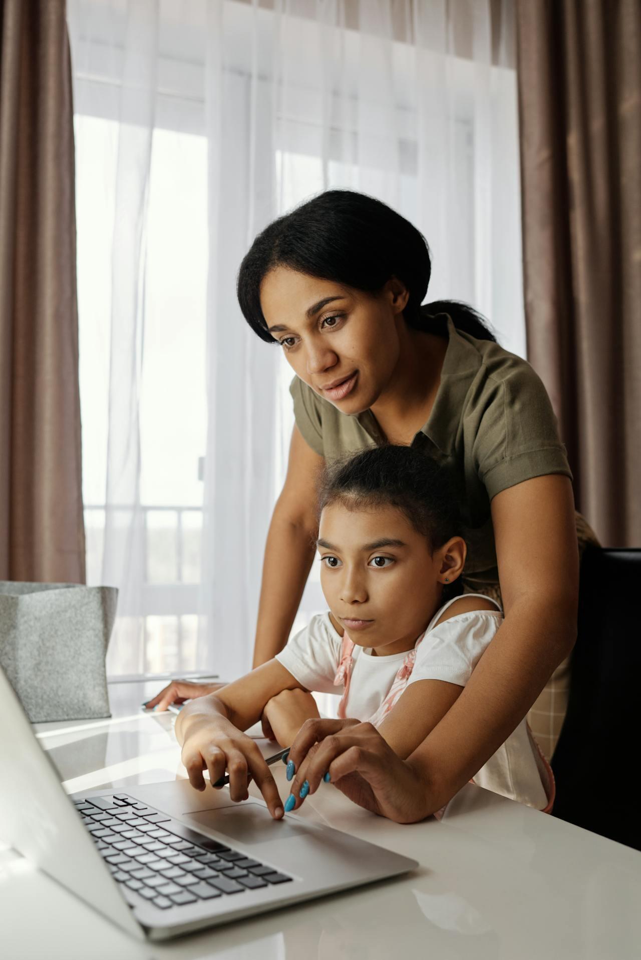 a parent helps her young child with homework on the computer