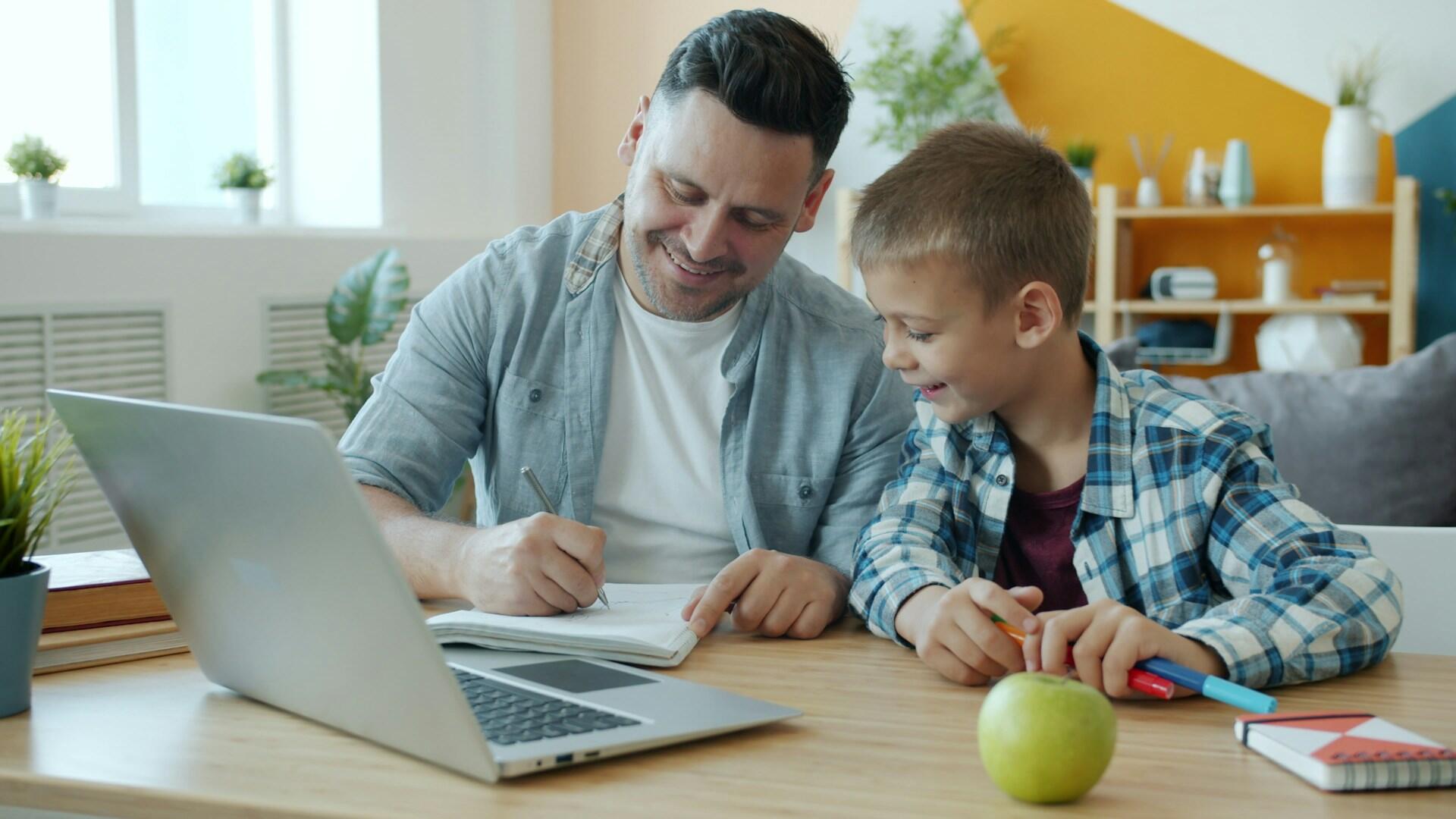 A father helps his son with homework, both are happy