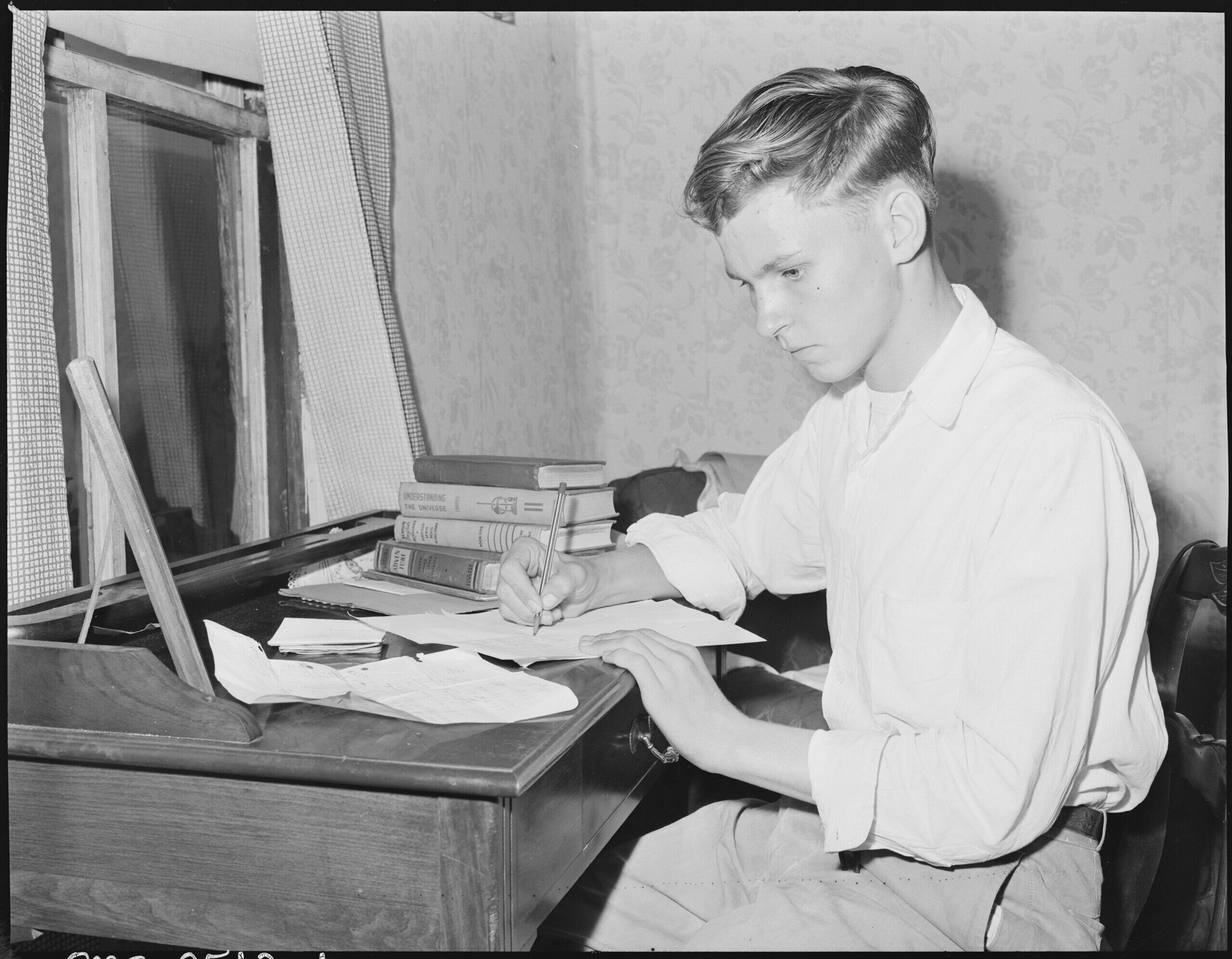 black and white photo of young man completing a homework assignment