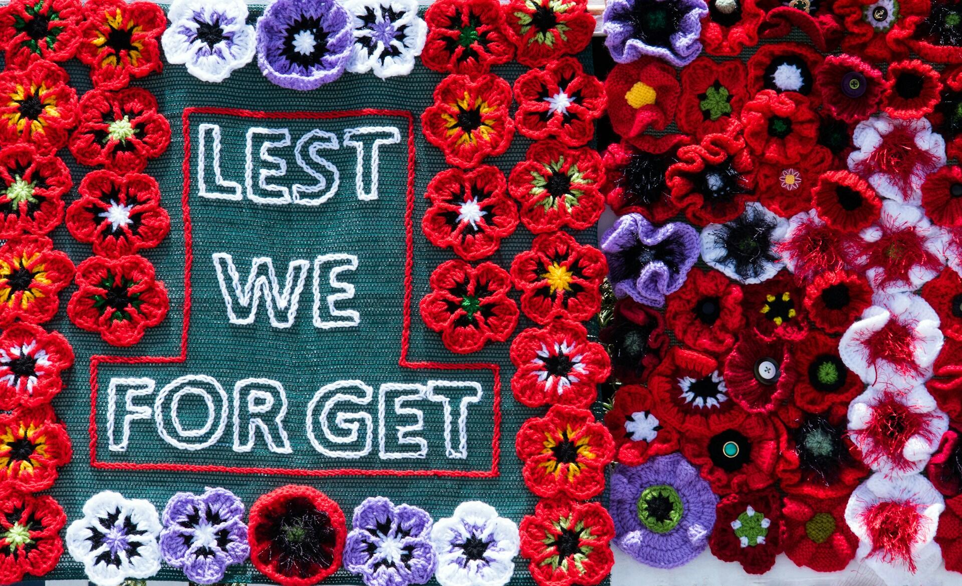 A handmade banner made of crocheted poppies and a green panel about remembrance