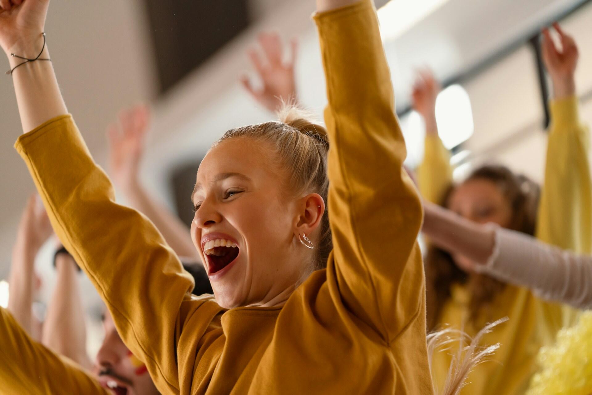 A group of singers with their arms up, smiling.
