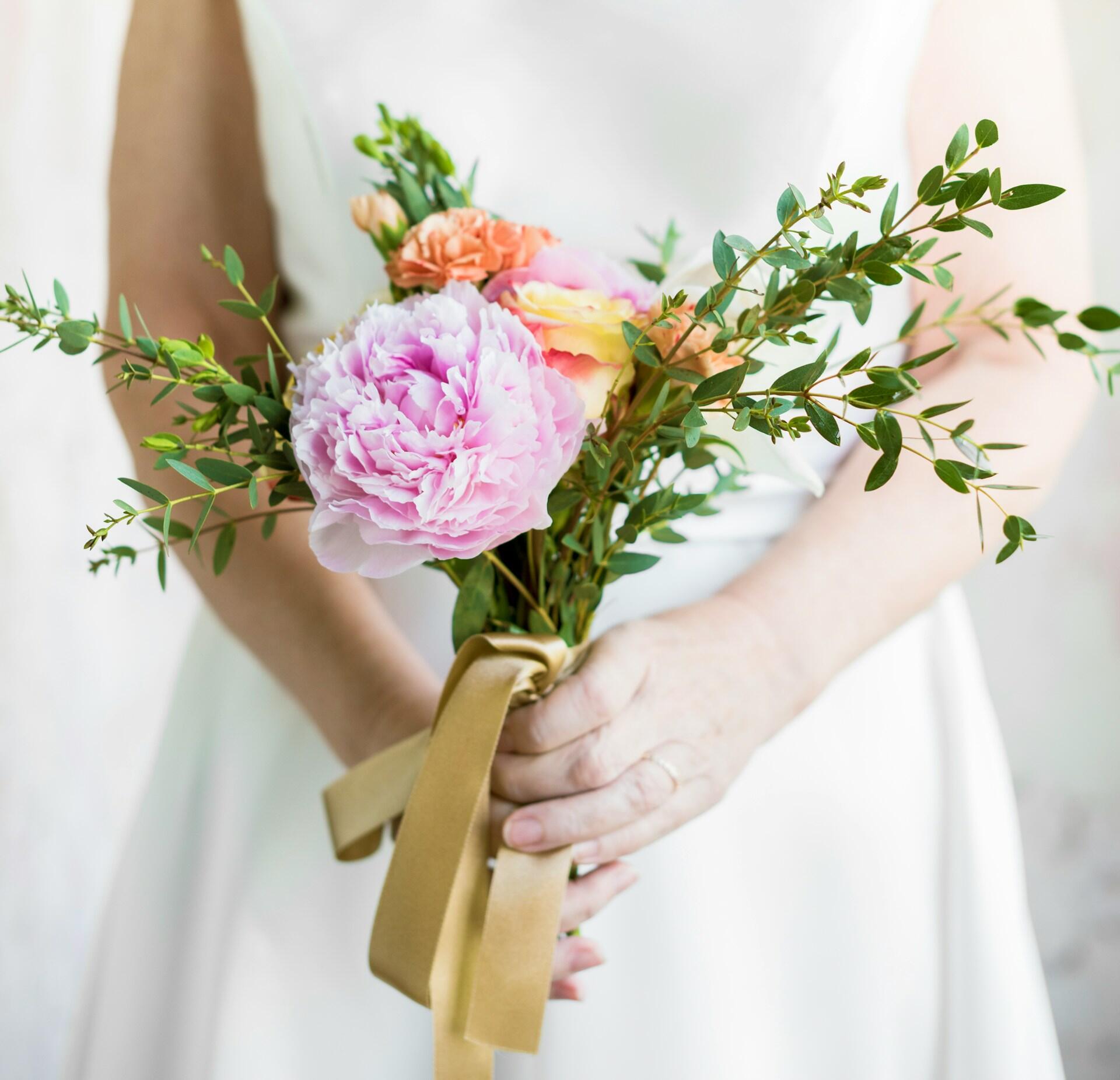 A bride wearing white holding a bouquet.