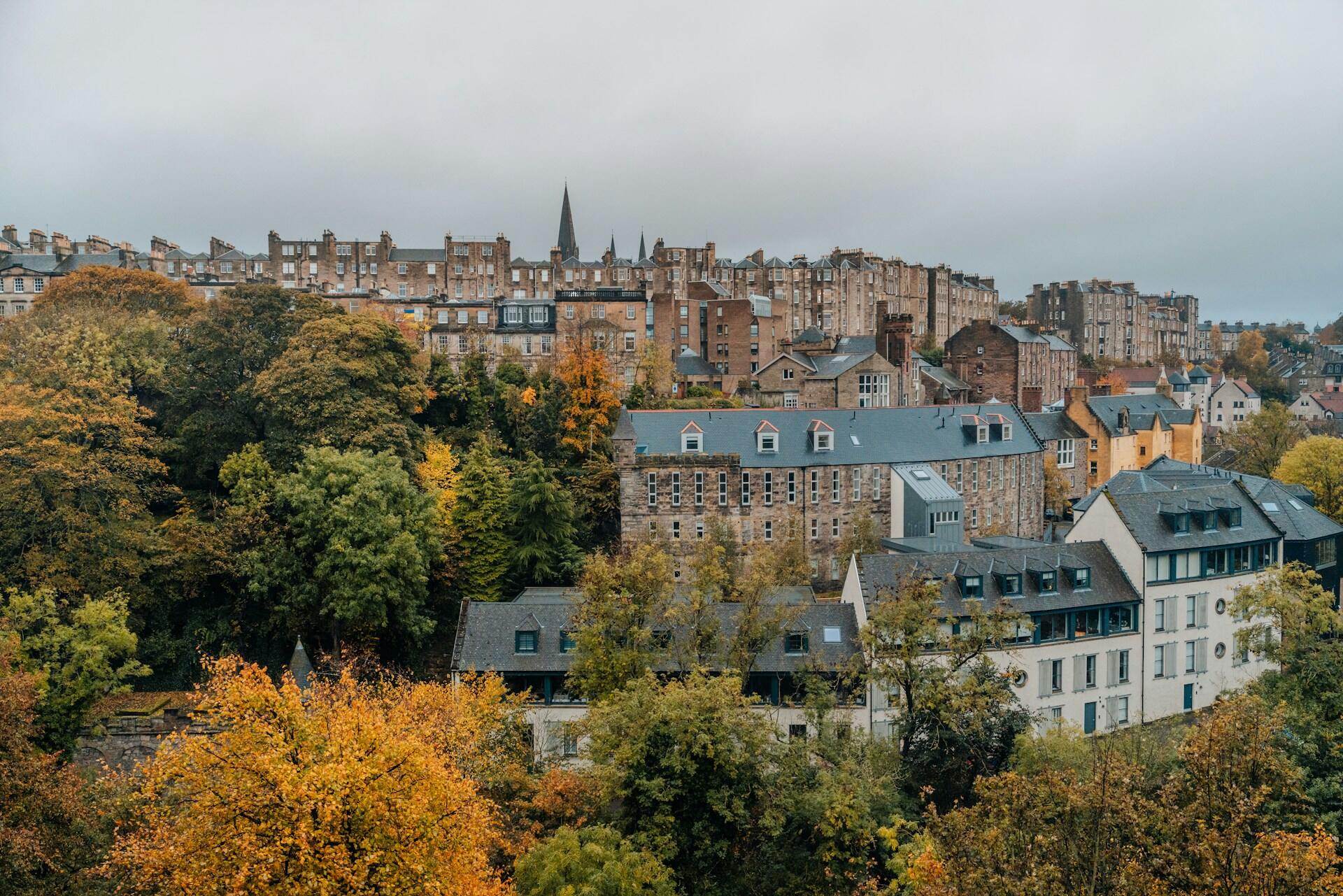 A hillside view of a British cityscape with autumn foliage, featuring historic buildings.