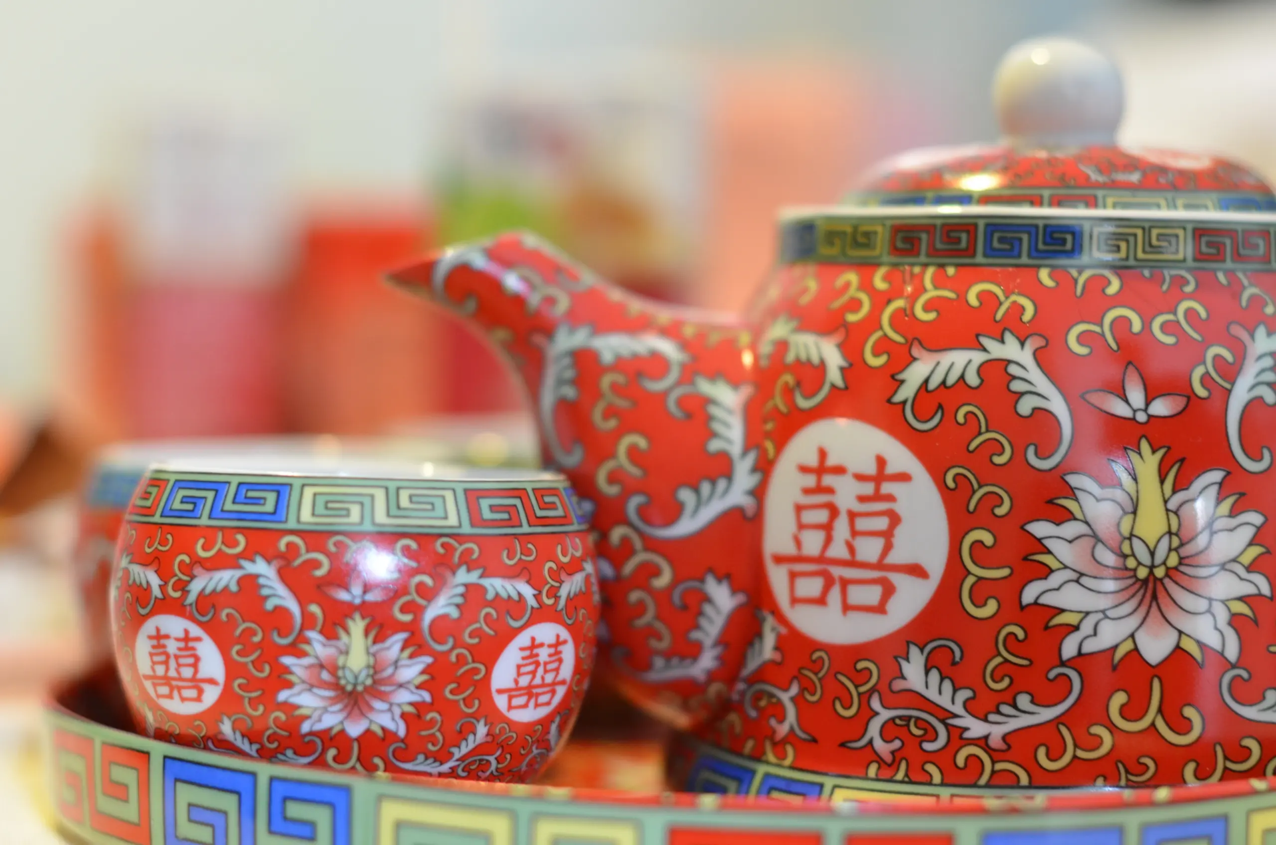 A red Chinese teapot and cup, adorned with intricate patterns.