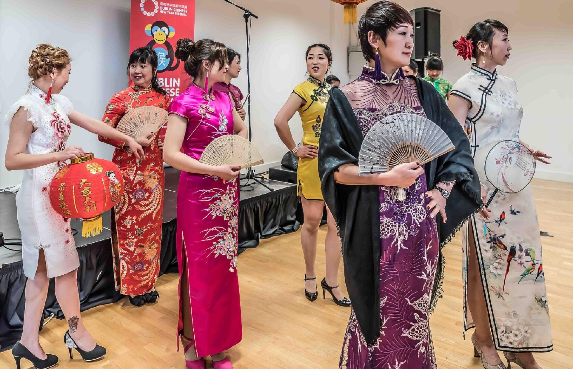 Women posing in Chinese qipao while holding fans.
