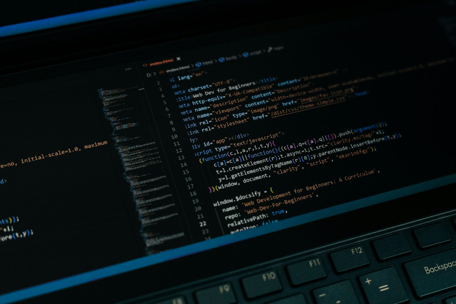 A close-up of a laptop screen displaying various lines of HTML and JavaScript code in a dark theme.