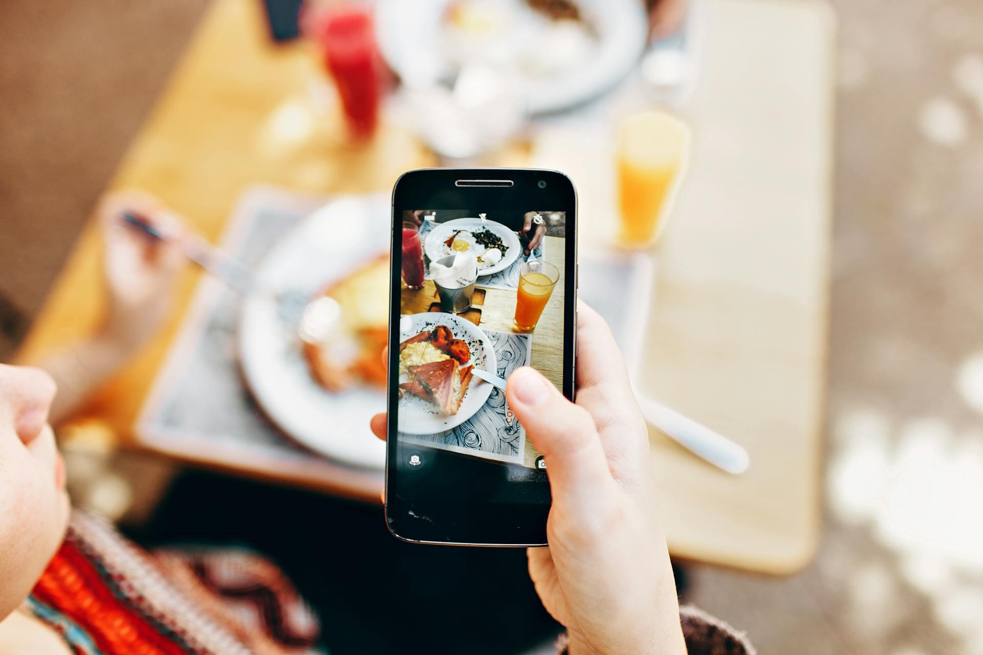 person taking a photo of a nice cafe spread on their phone perfect for Instagram