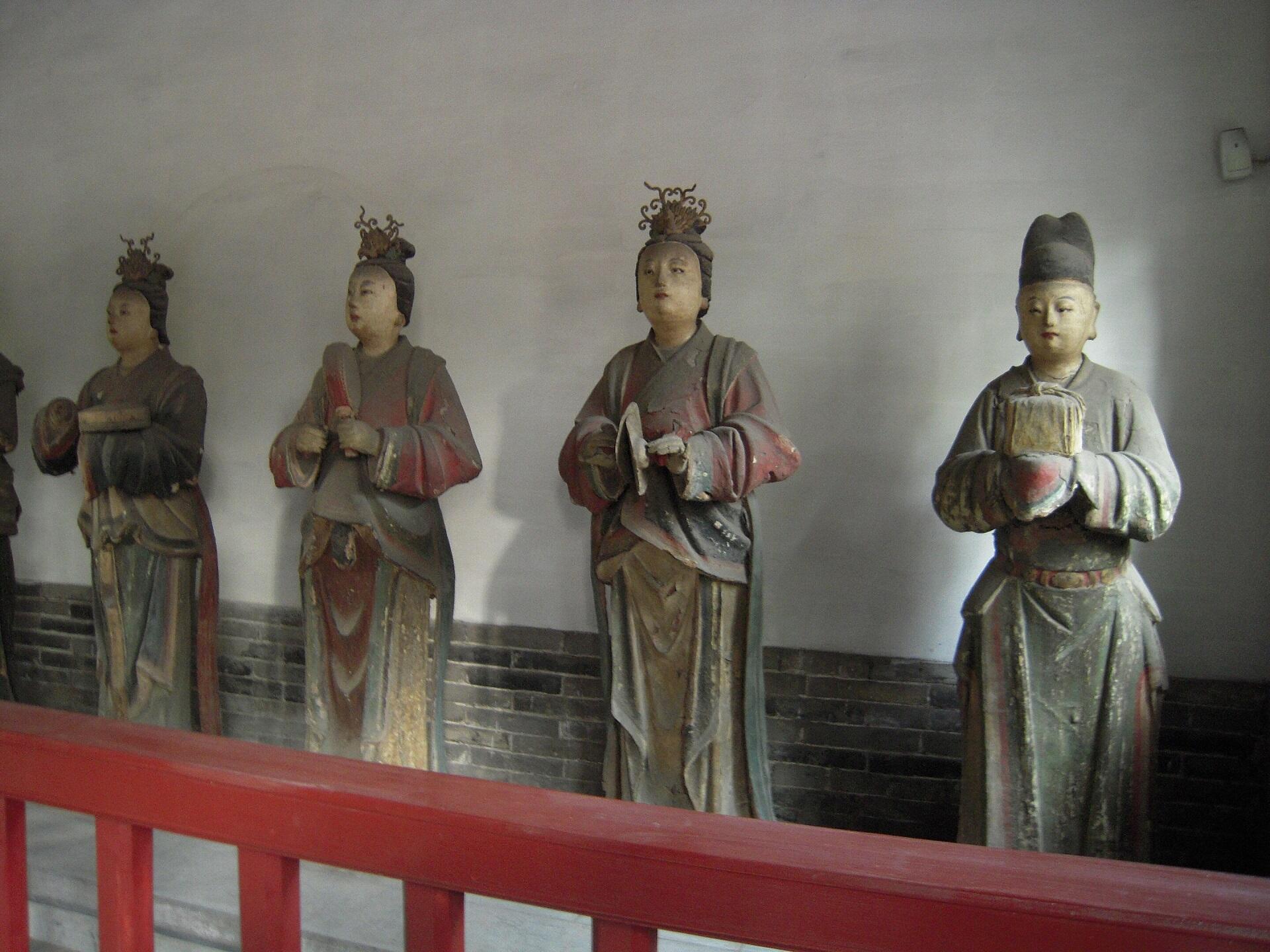 Four statues wearing ancient Chinese clothing styles. 