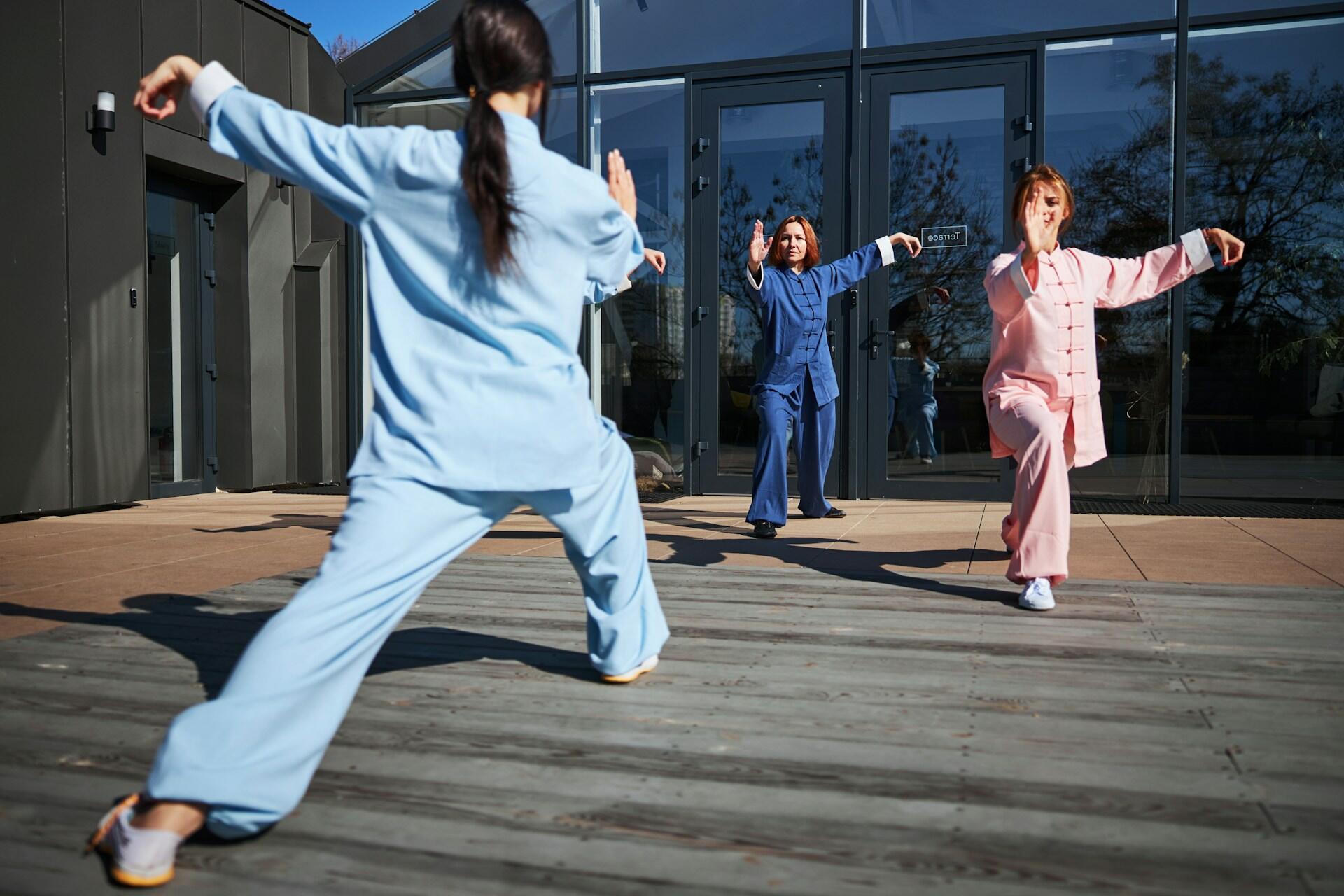 Three women wearing colourful Chinese tang suits on a sunny day.
