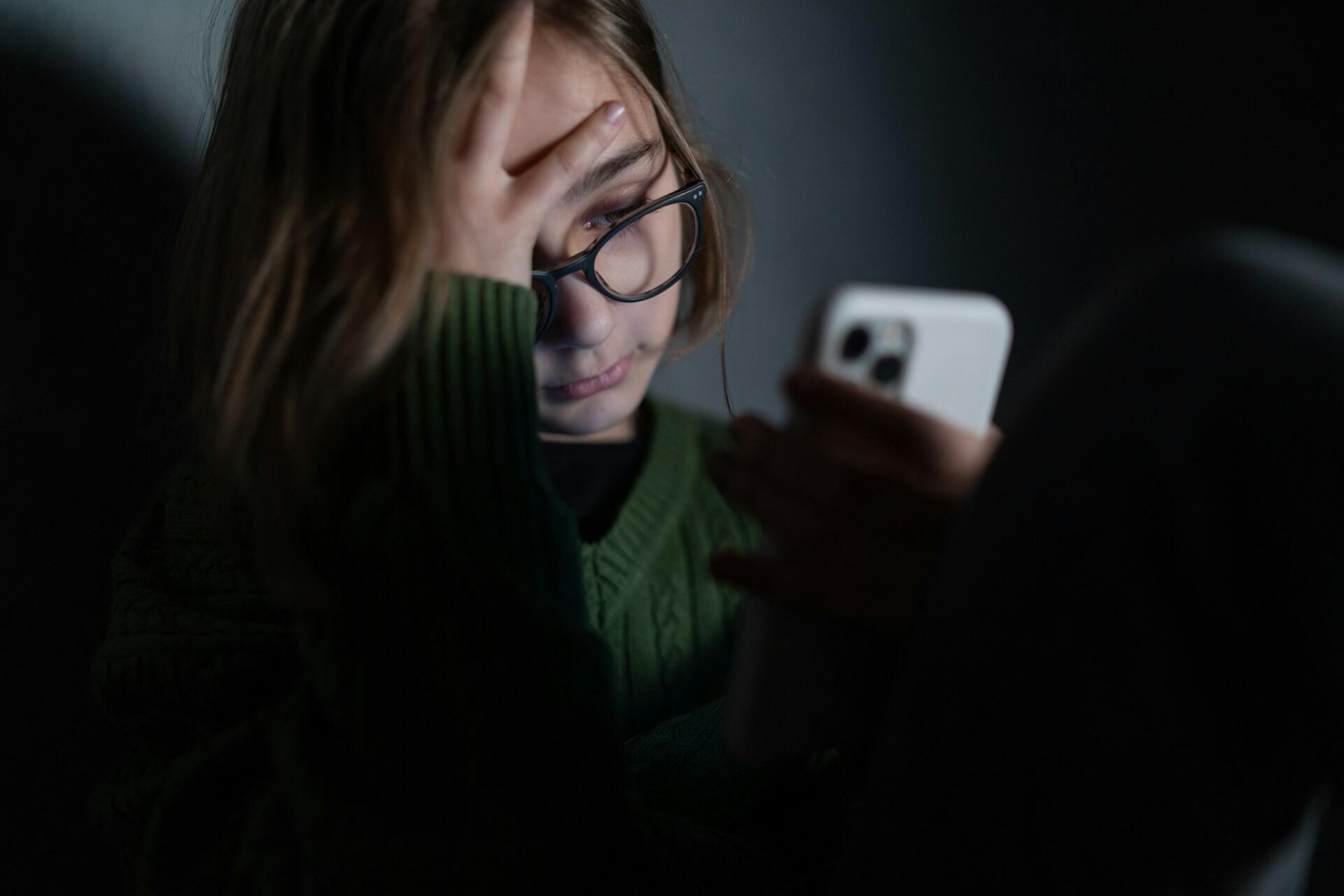 teen looking distressed while holding a phone