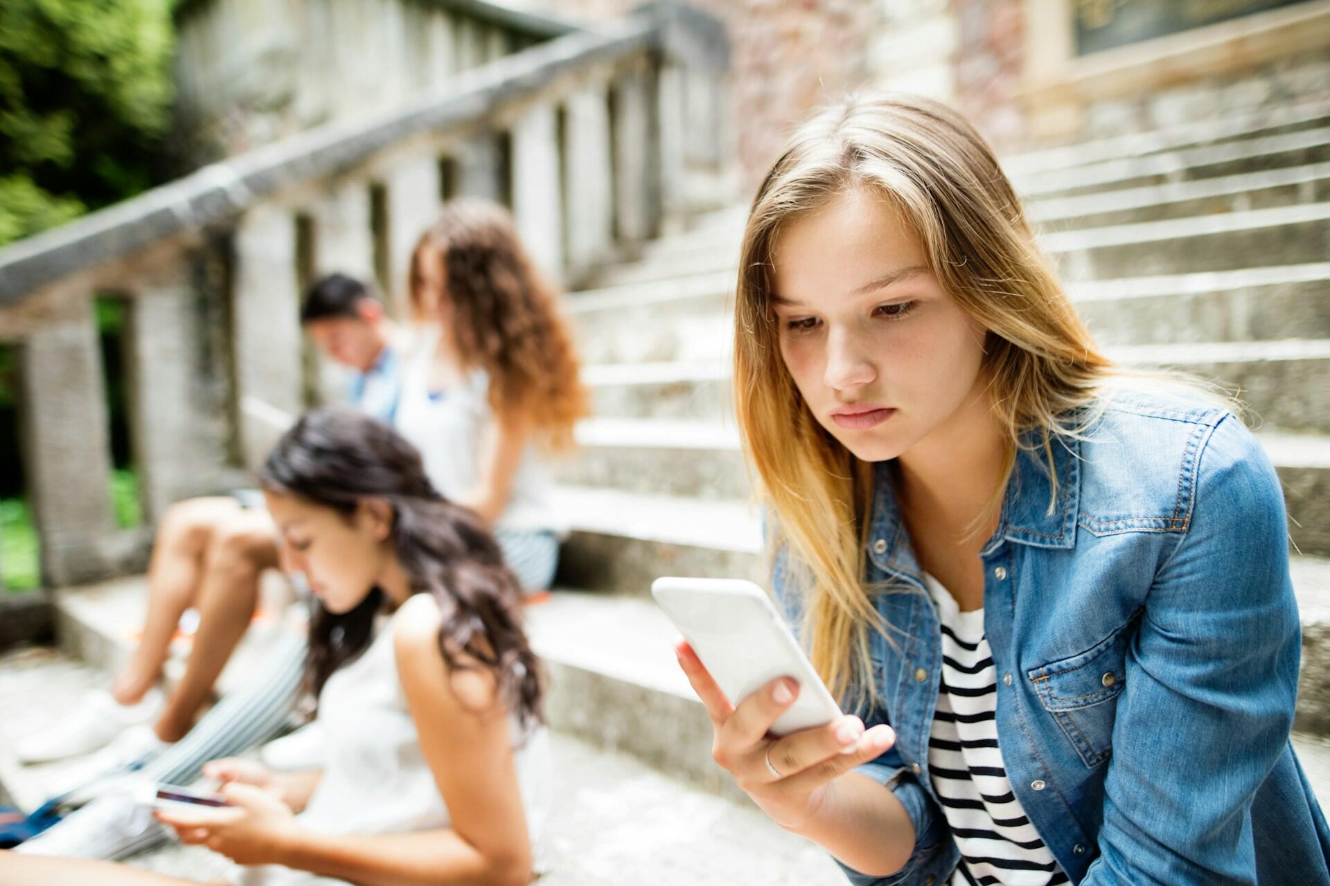 group on teens sitting on stairs using phones