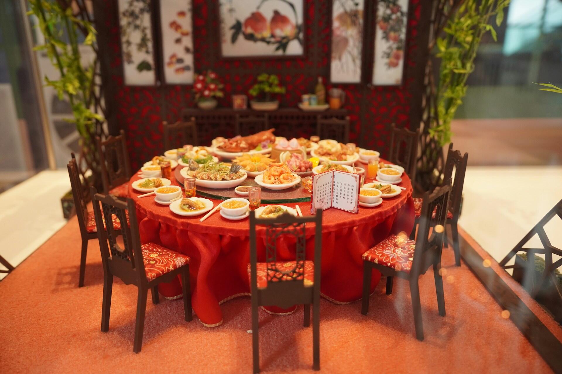 A round table with red tablecloth, laden with food. 