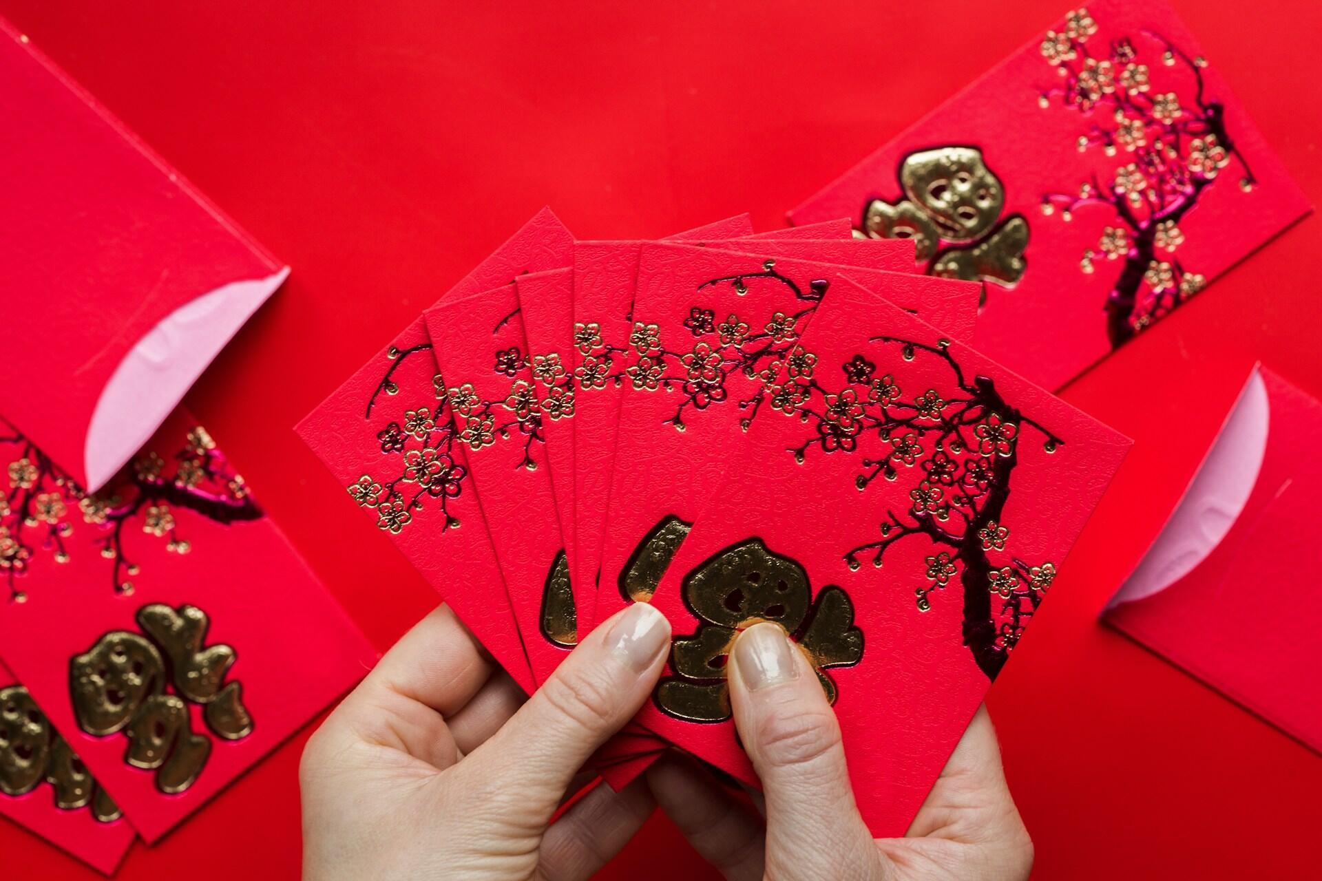 A person holding a fan of red envelopes. 