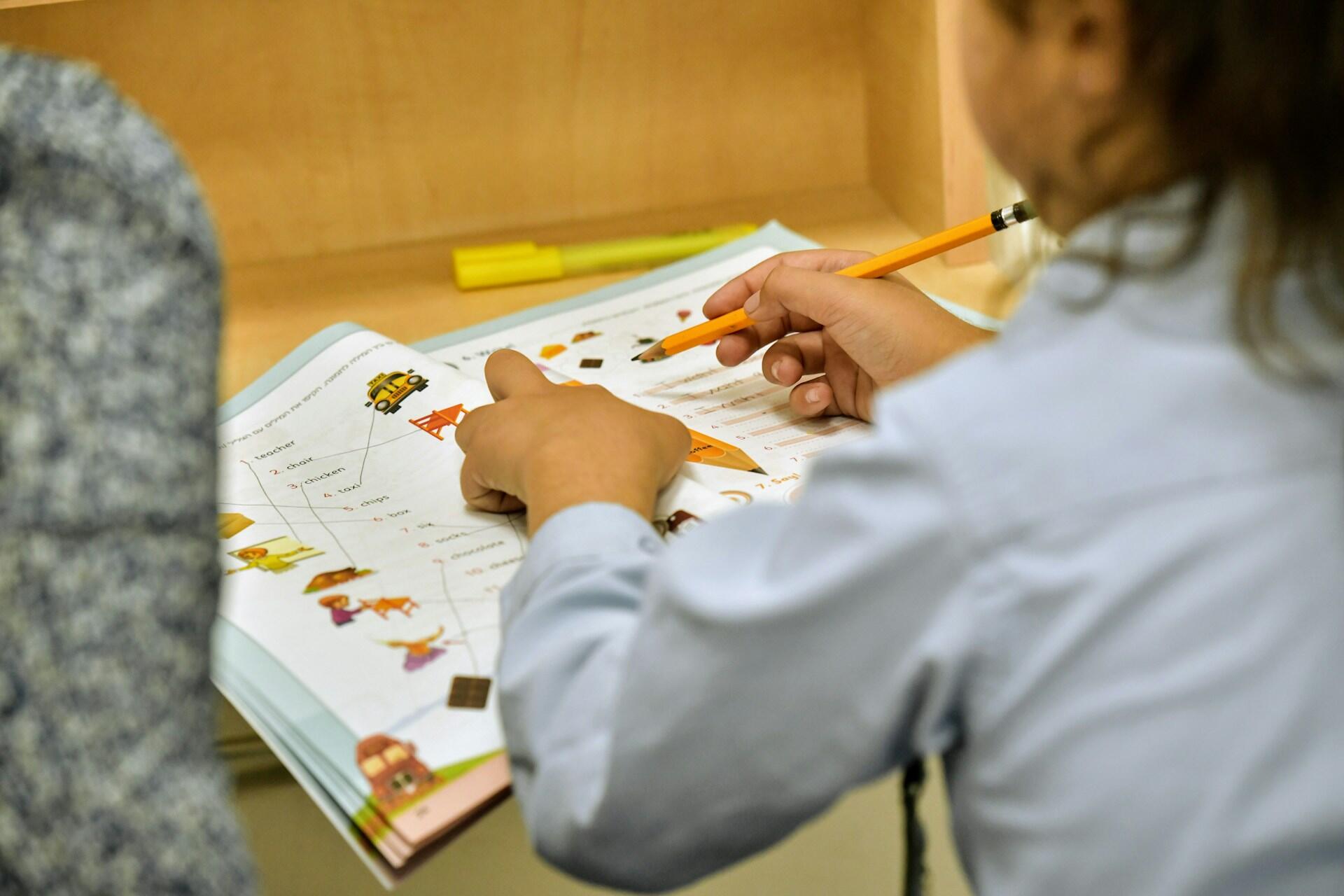Child completing school exercises with a pencil at a desk.