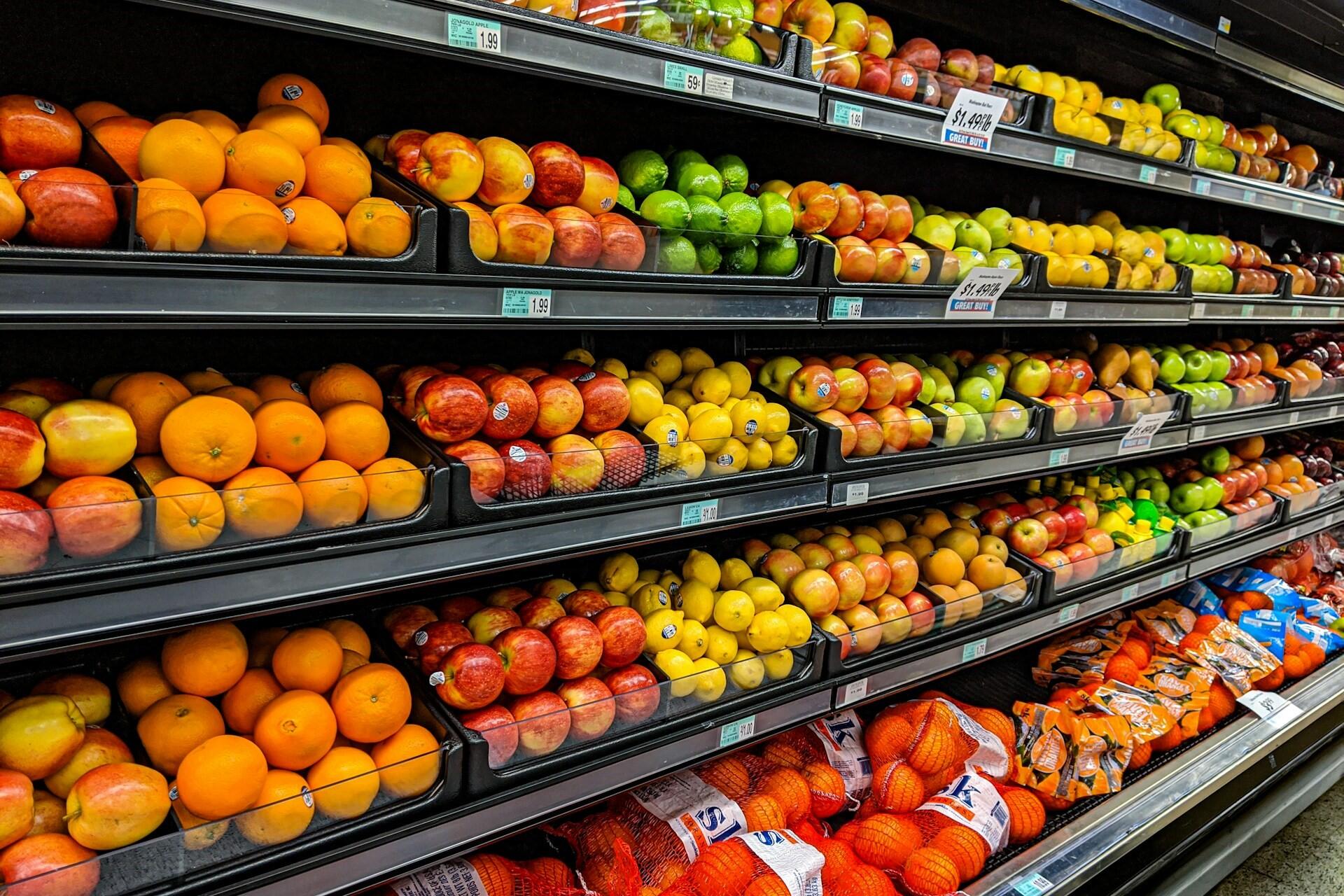 Fresh fruit displayed on shelves in a supermarket aisle.