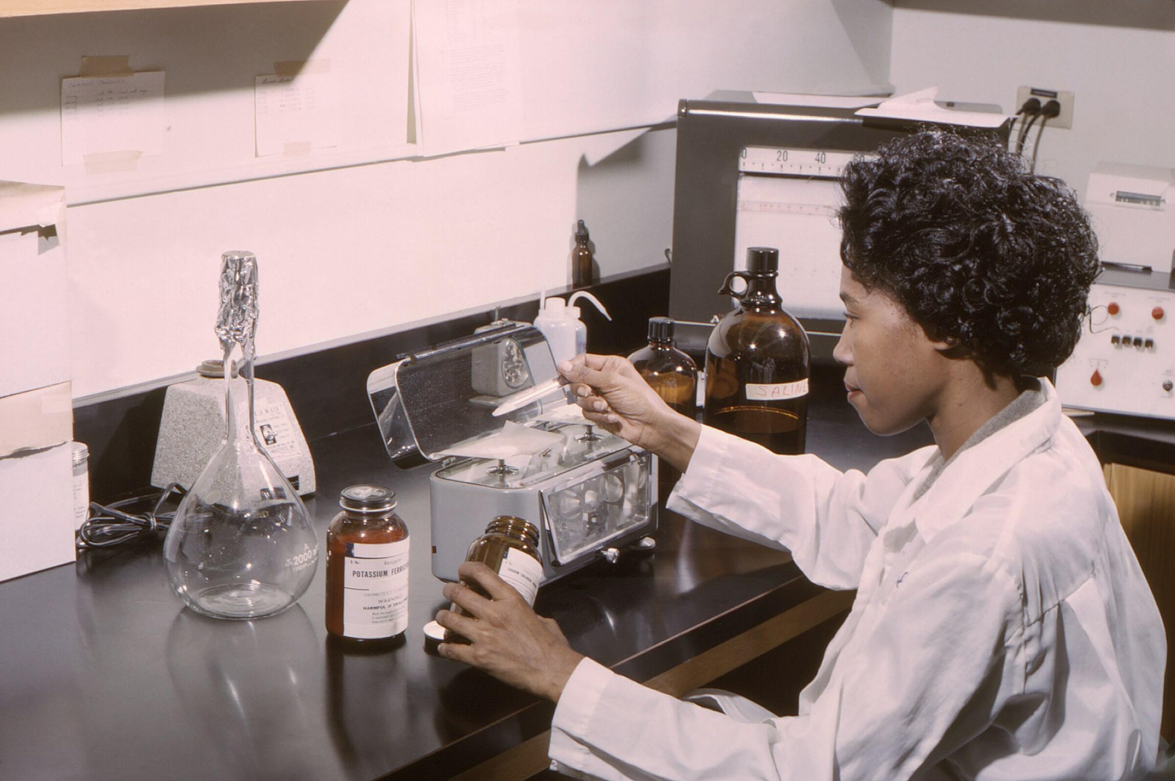 A laboratory technician measuring out various powdered chemicals.