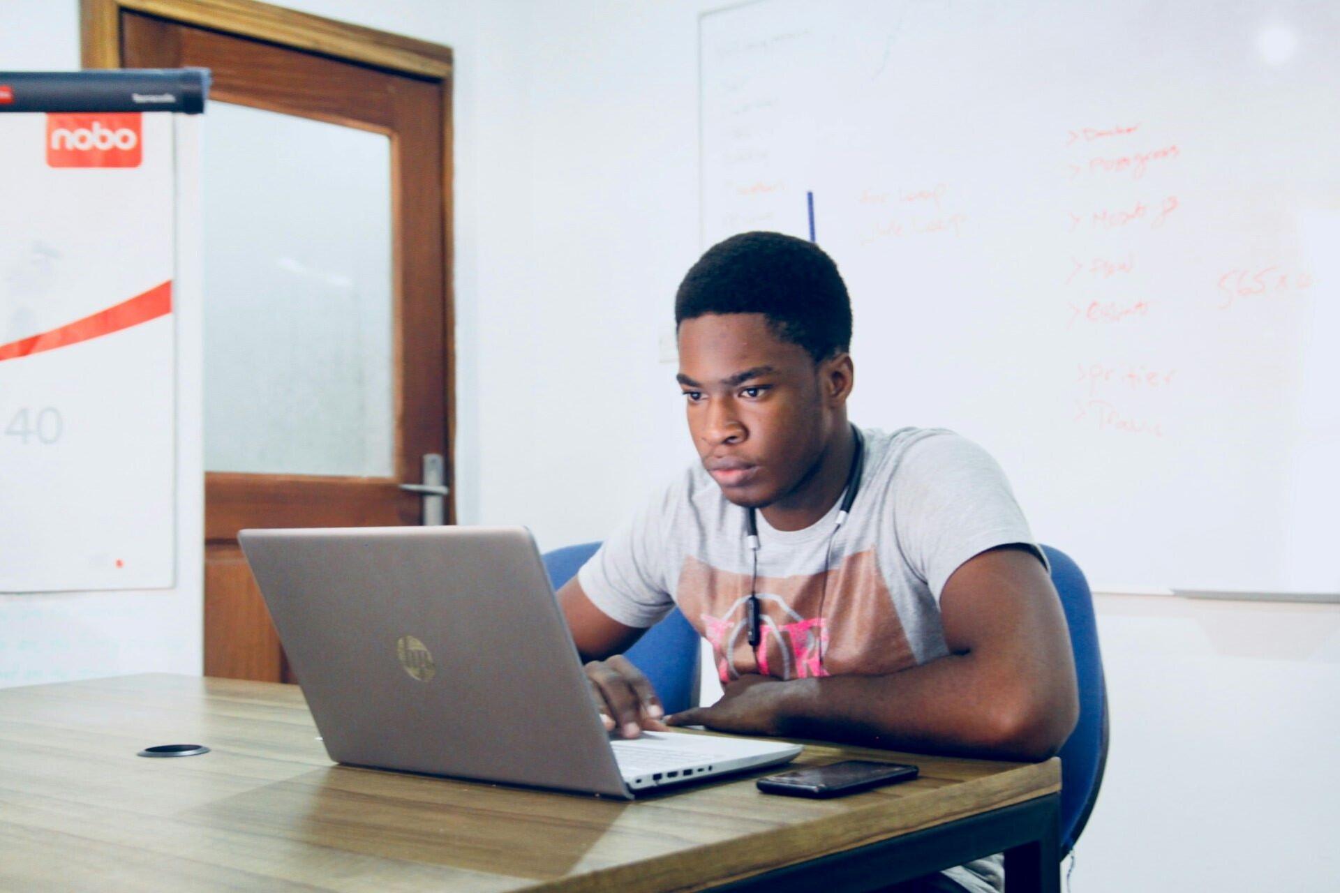 Student sitting at a desk and working on a laptop in a classroom setting.