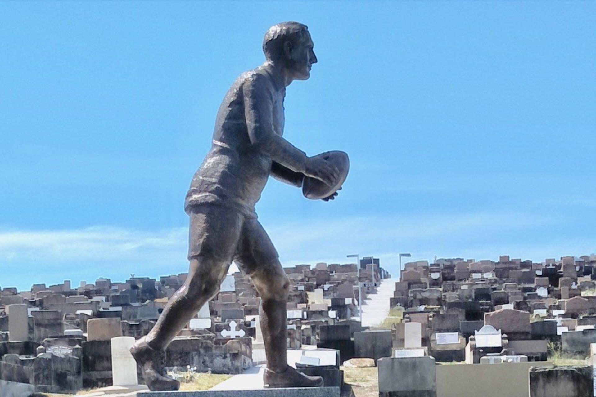 Statue of Dally Messenger holding a rugby ball in Waverley Cemetery, Sydney