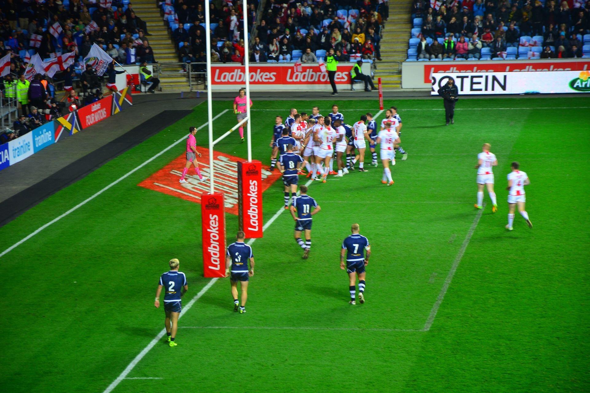 England and Scotland rugby league players gathered near the goalposts during an international match