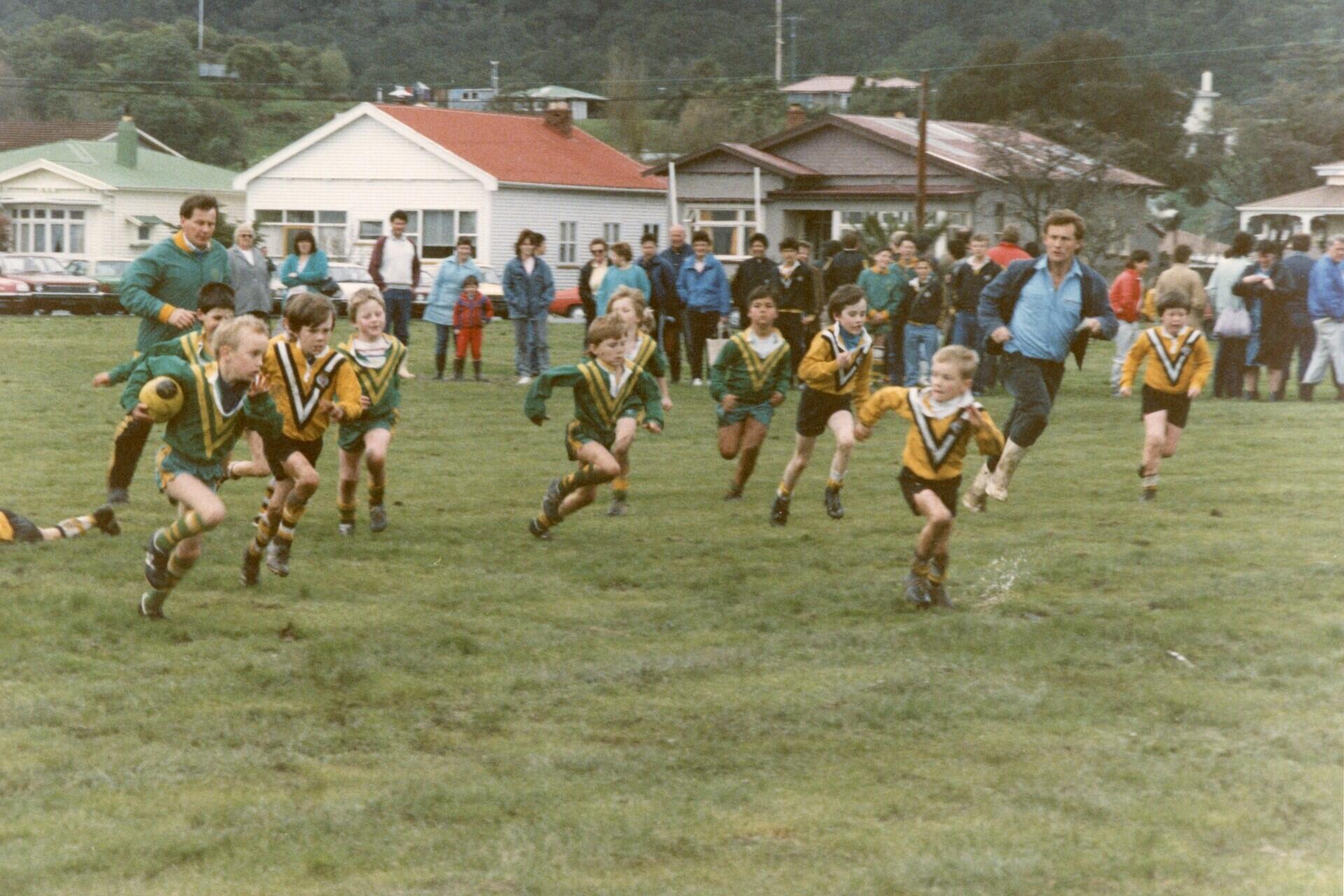 Children playing rugby league during a youth match on a grassy field