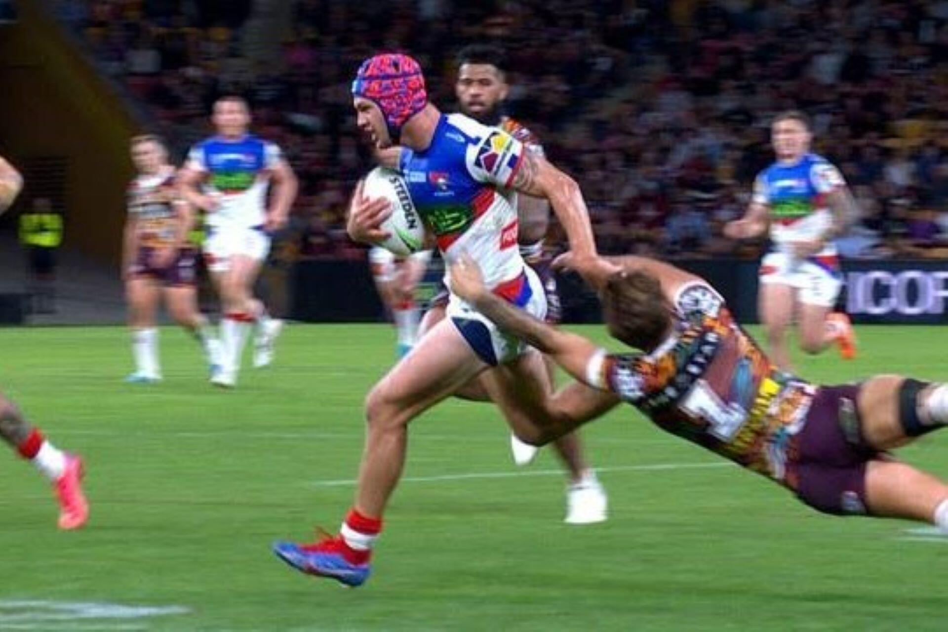 Rugby league player running with the ball while being tackled during an NRL match