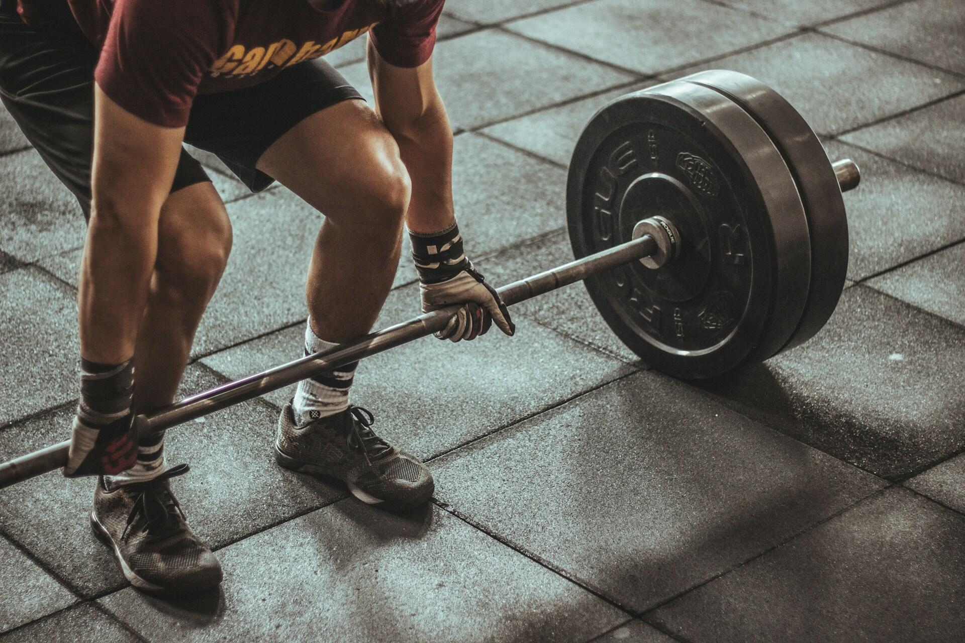 Athlete preparing to lift a loaded barbell during a strength training workout in a gym.
