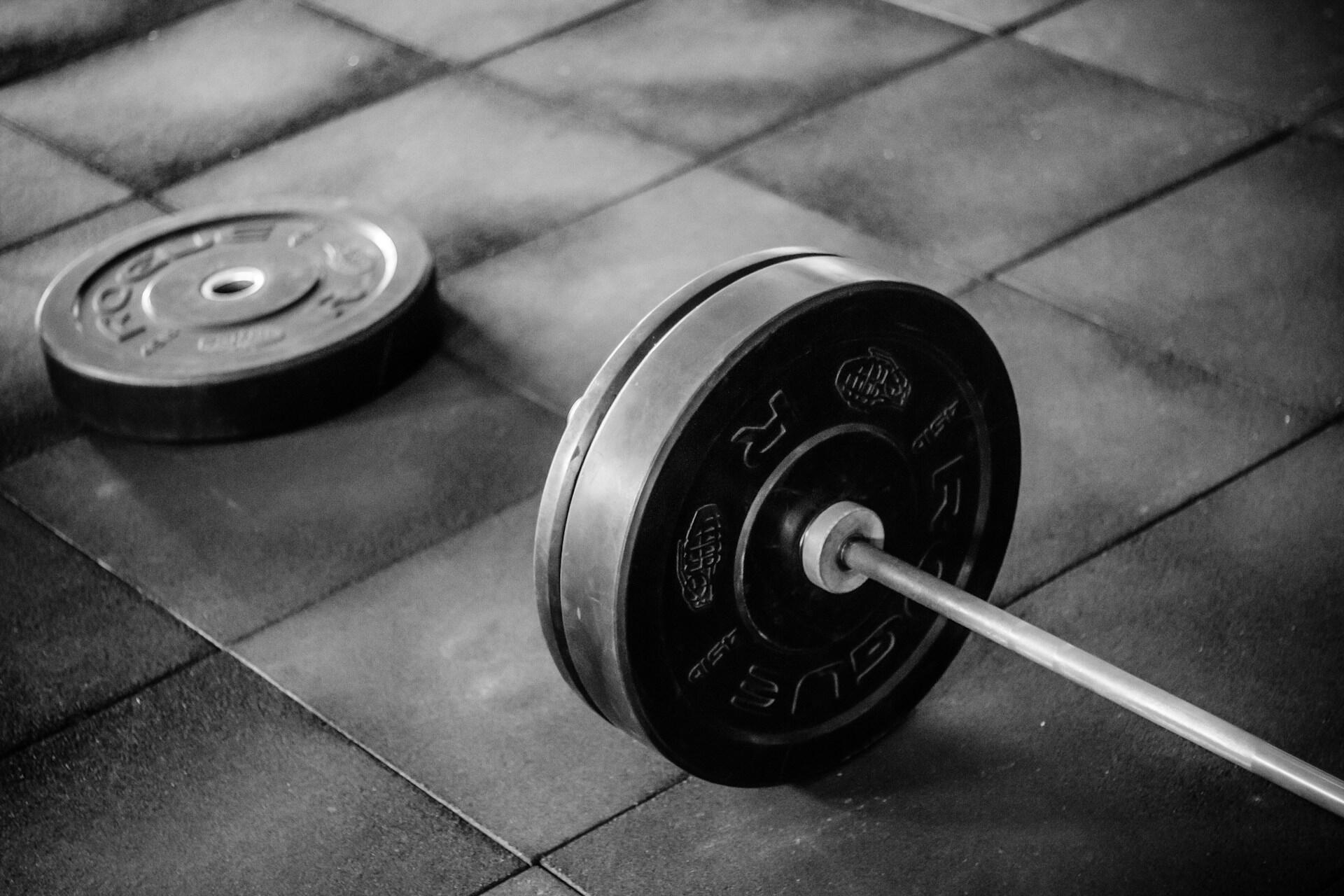 Loaded barbell with weight plates resting on a gym training floor.