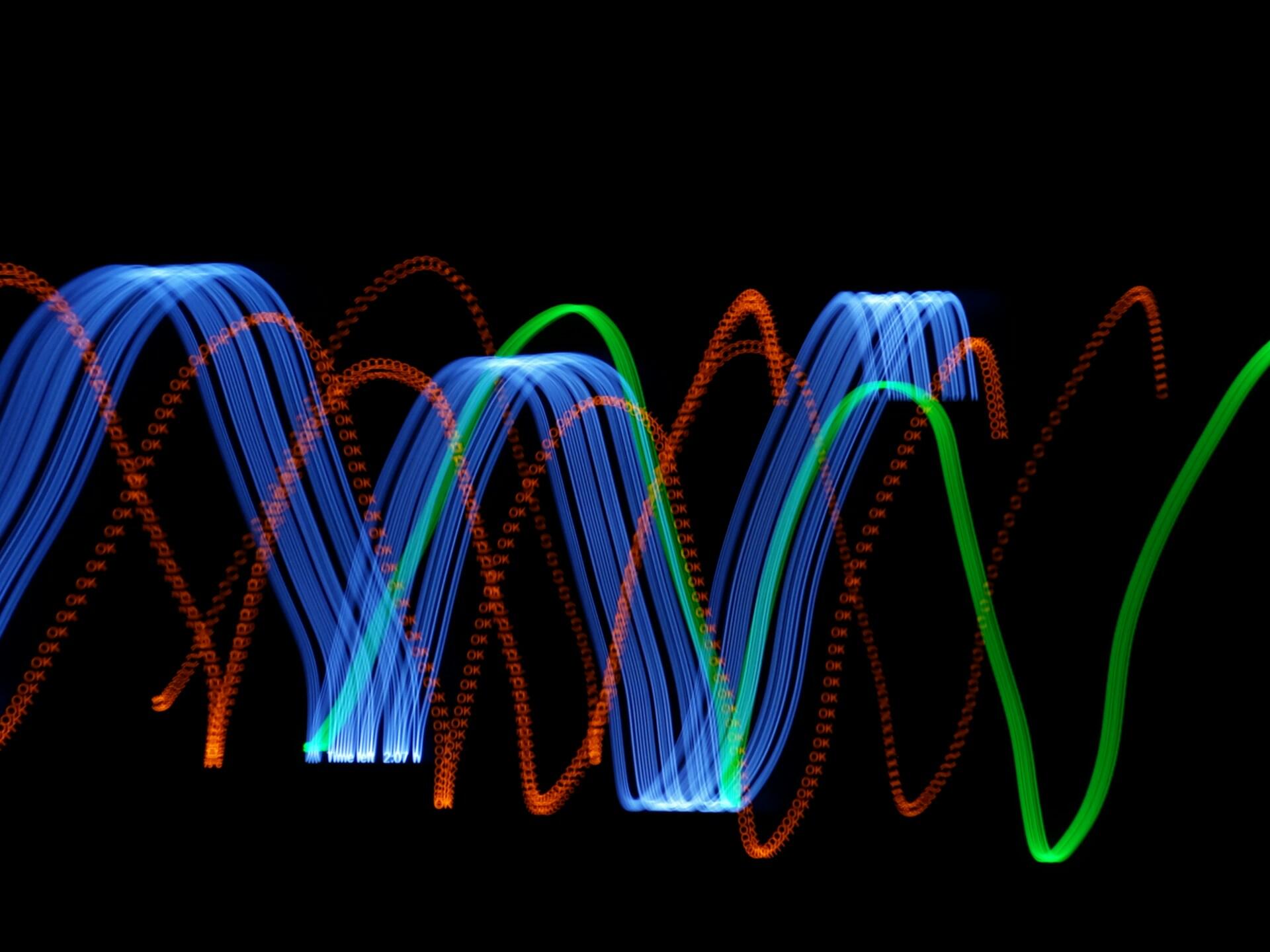 Green, blue and red lights creating waves against a black background.