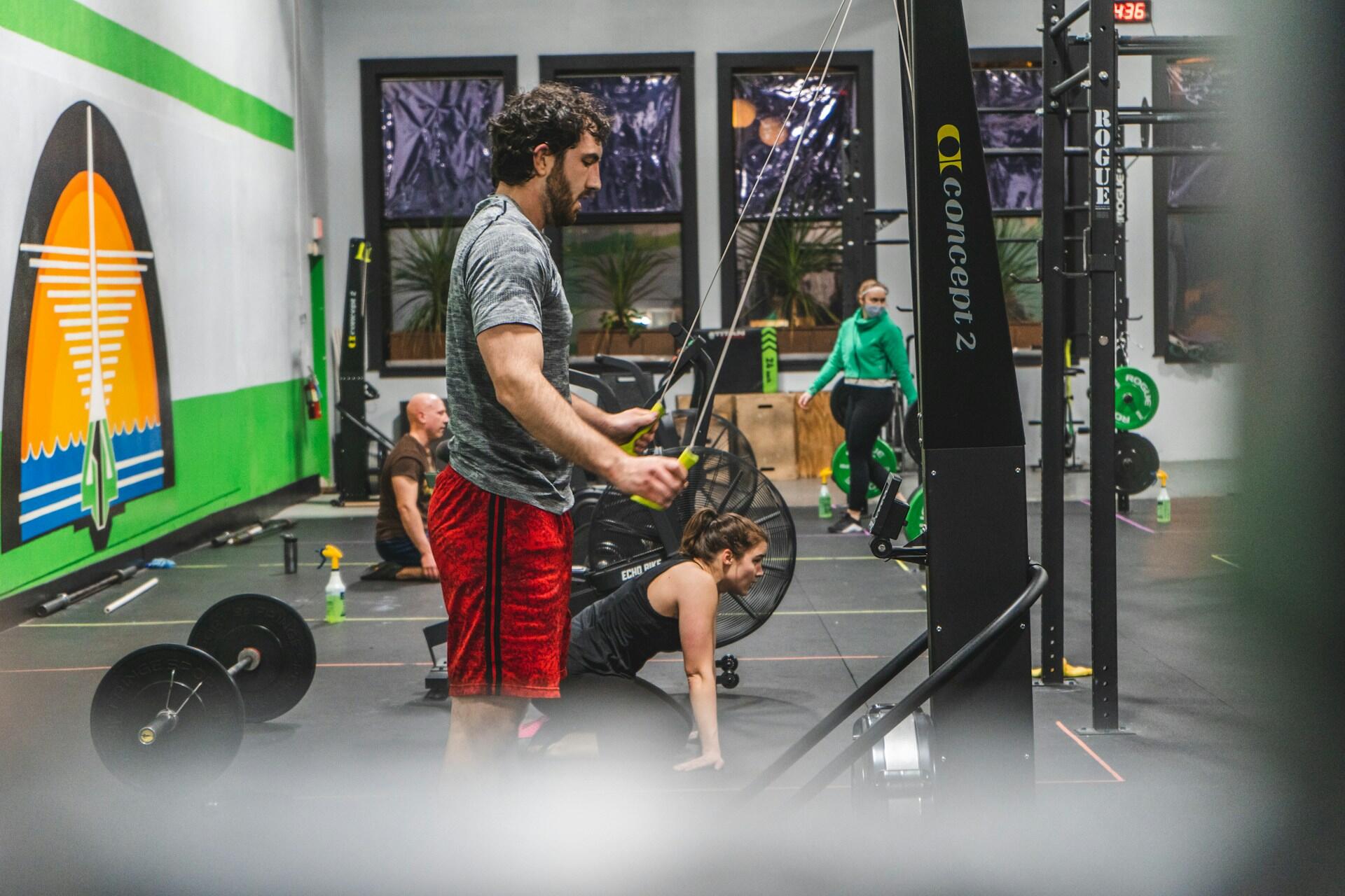 Athlete using a Concept2 rowing machine in a functional training gym with other athletes exercising nearby