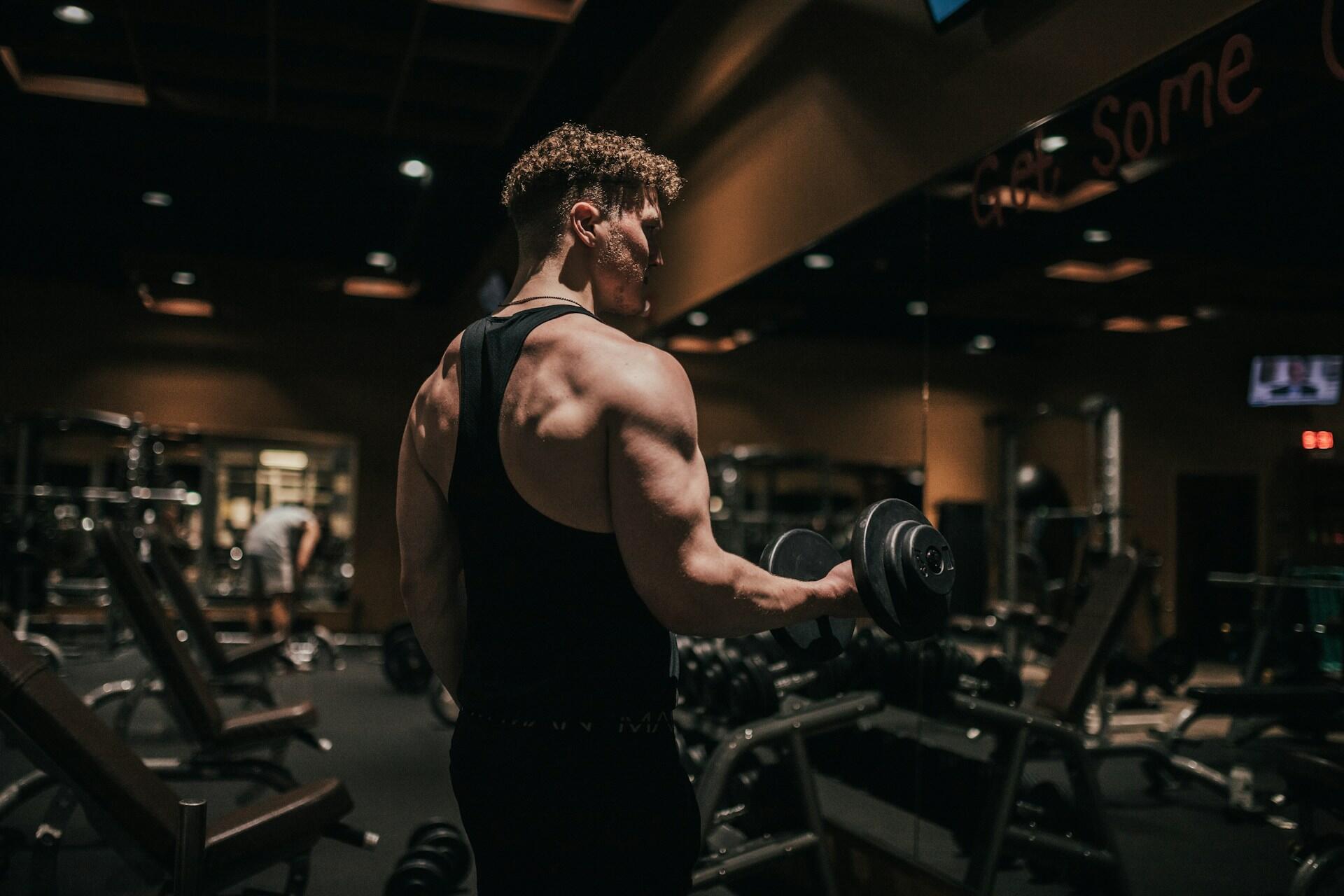 Athlete lifting a dumbbell during strength training inside a modern gym.