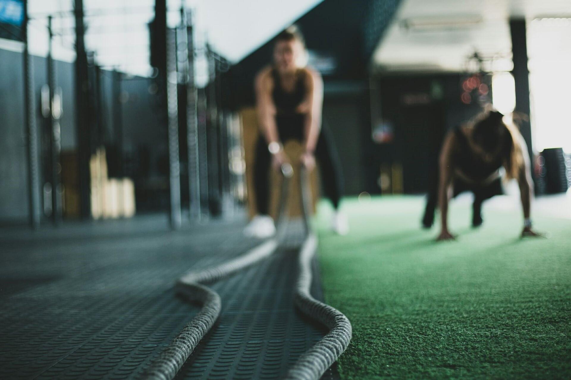 Athletes using battle ropes during a high-intensity conditioning workout in a functional fitness gym