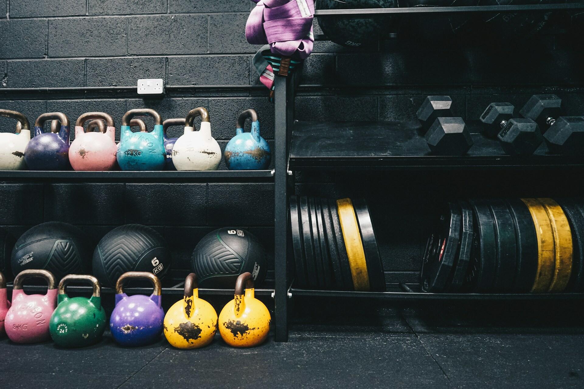 Rack of kettlebells, medicine balls, and weight plates inside a functional training gym