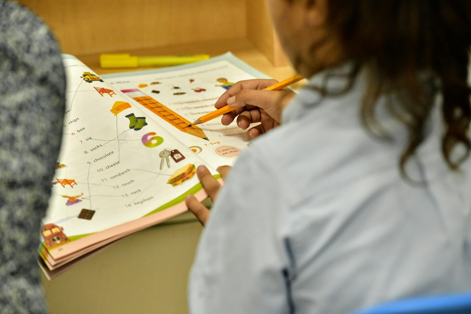 Person holding pencil working on worksheet with images.
