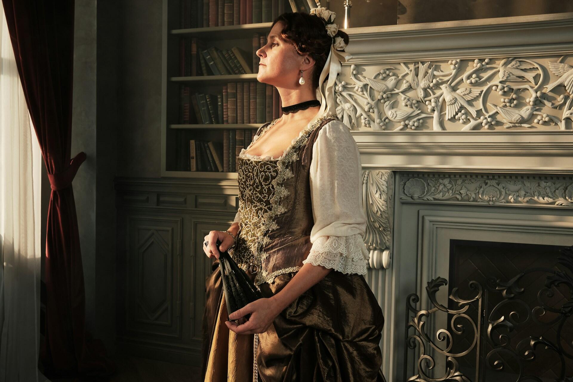 Portrait of a woman in medieval clothes in a royal interior.