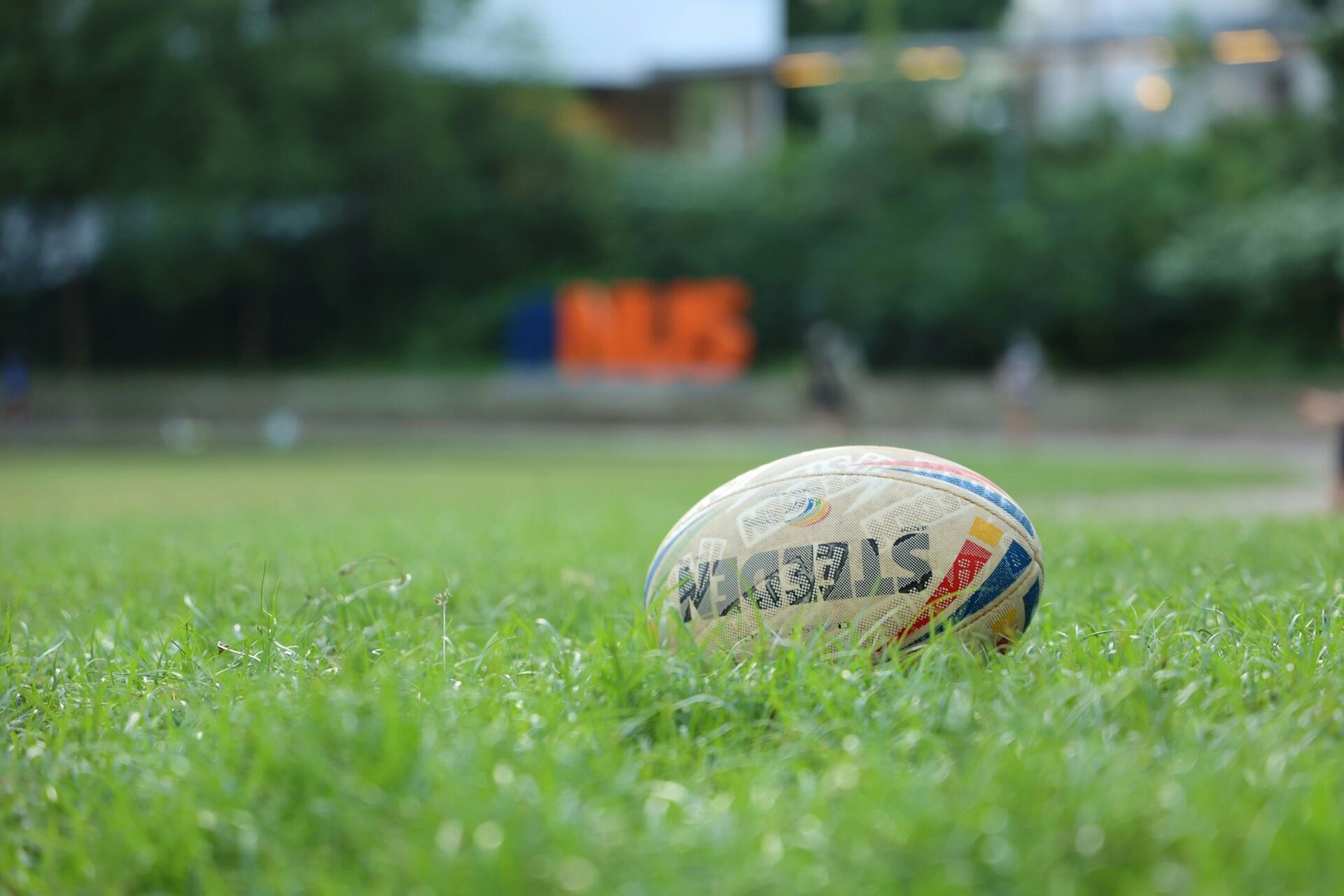 Rugby ball lying in green grass with a blurred background
