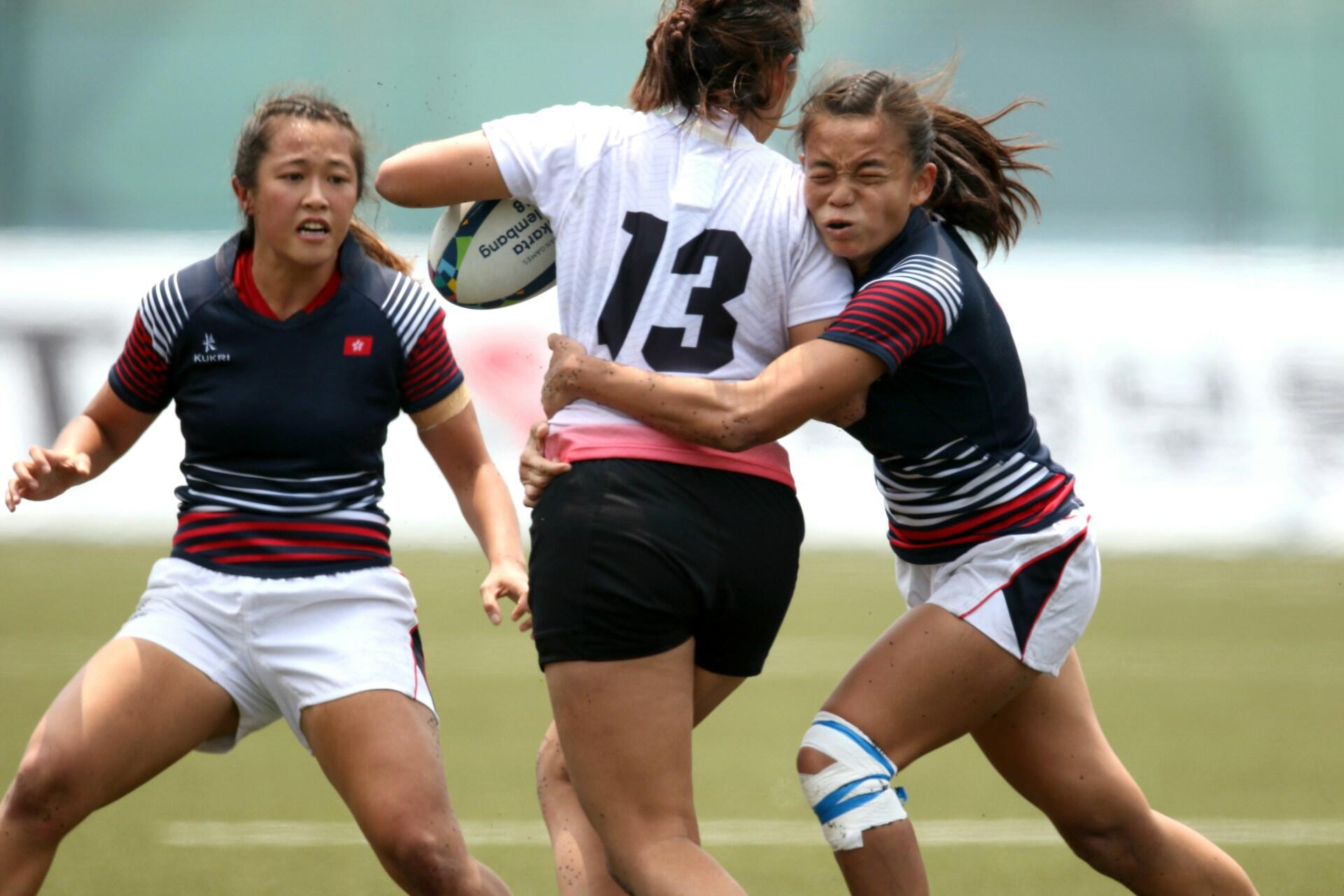 Two players tackling a player carrying a rugby ball
