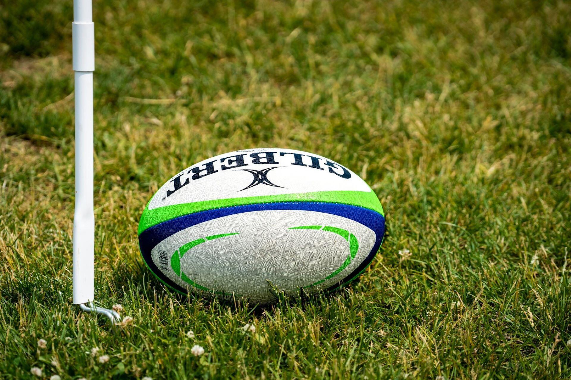 Rugby ball on grass beside a white corner post