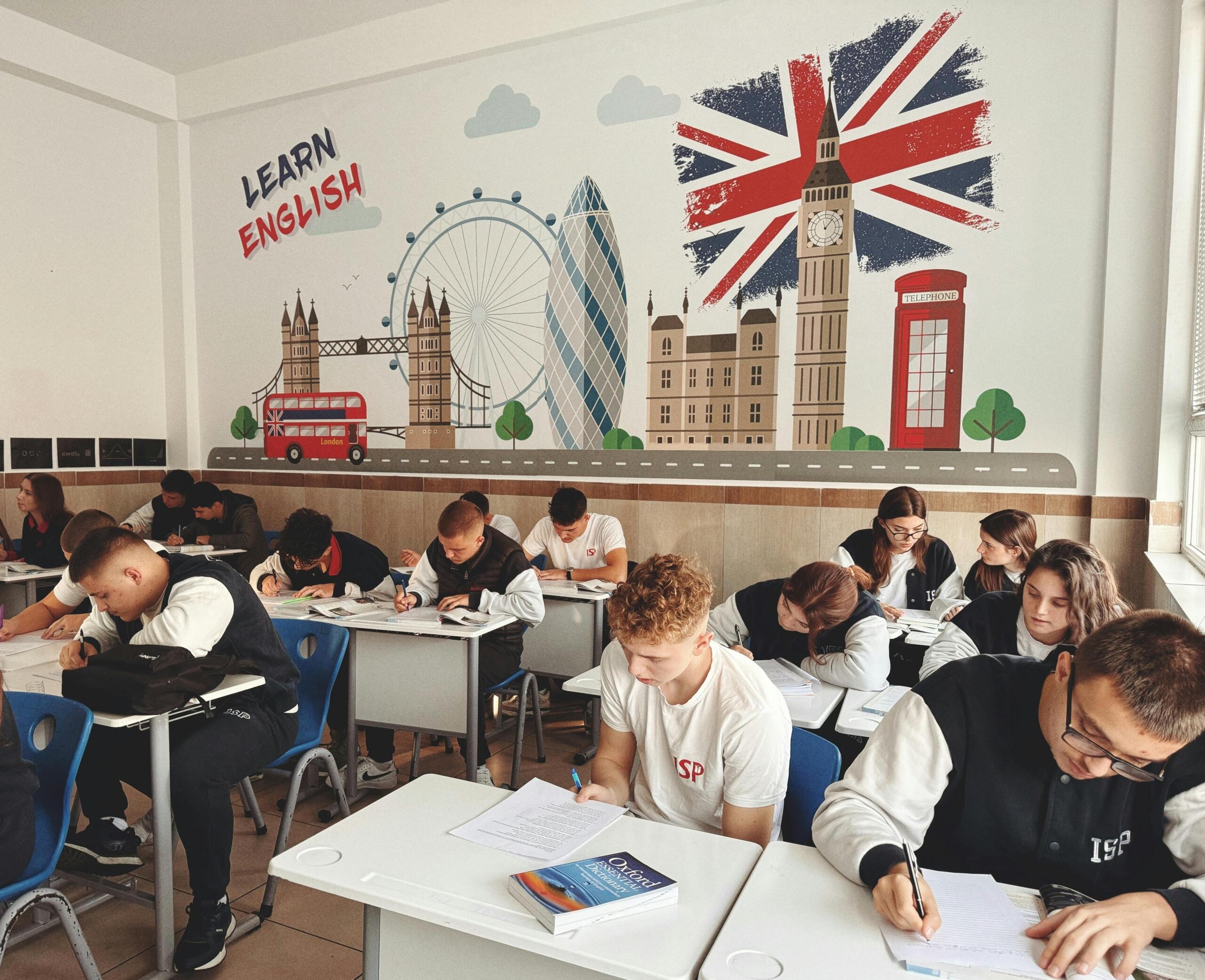 Učenici u učionici engleskog jezika ispred zida s natpisom Learn English i ilustracijom Londona tokom ESL lekcije