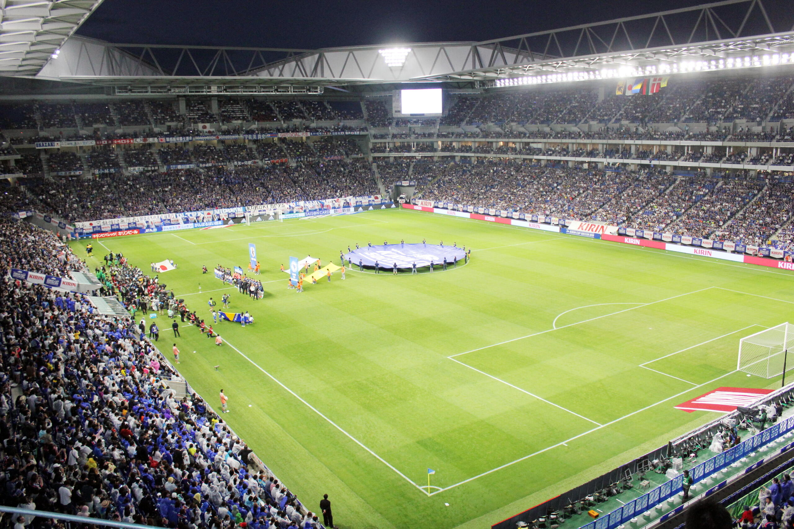 Panoramski snimak unutrašnjosti modernog fudbalskog stadiona tokom međunarodne utakmice, ilustruje globalni uspon koji opisuje BiH historija fudbala.