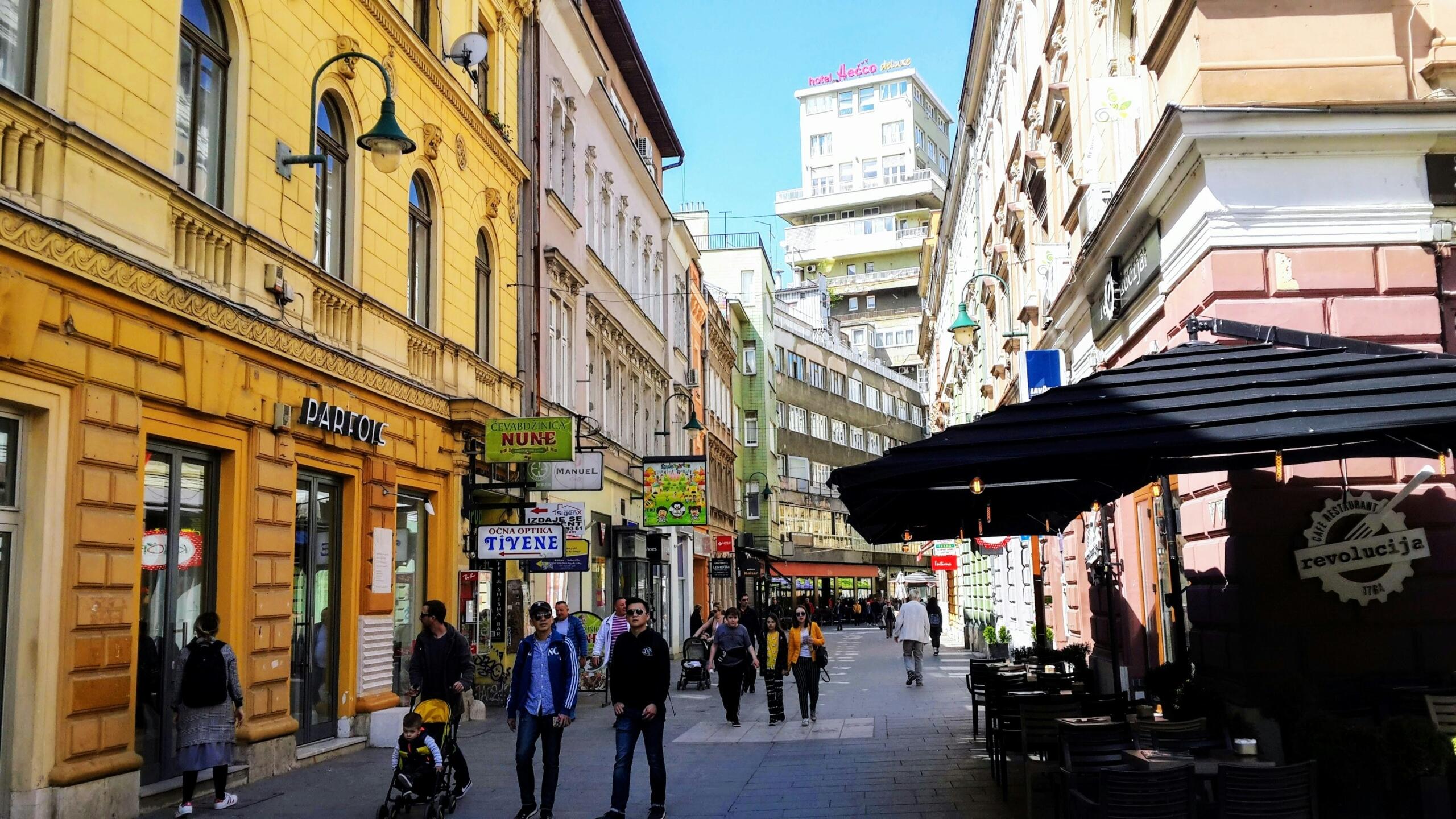 Užurbana atmosfera u centru Sarajeva s prolaznicima i turistima, ilustruje razvoj turizma i globalno brendiranje kroz međunarodna postignuća reprezentacije BiH.