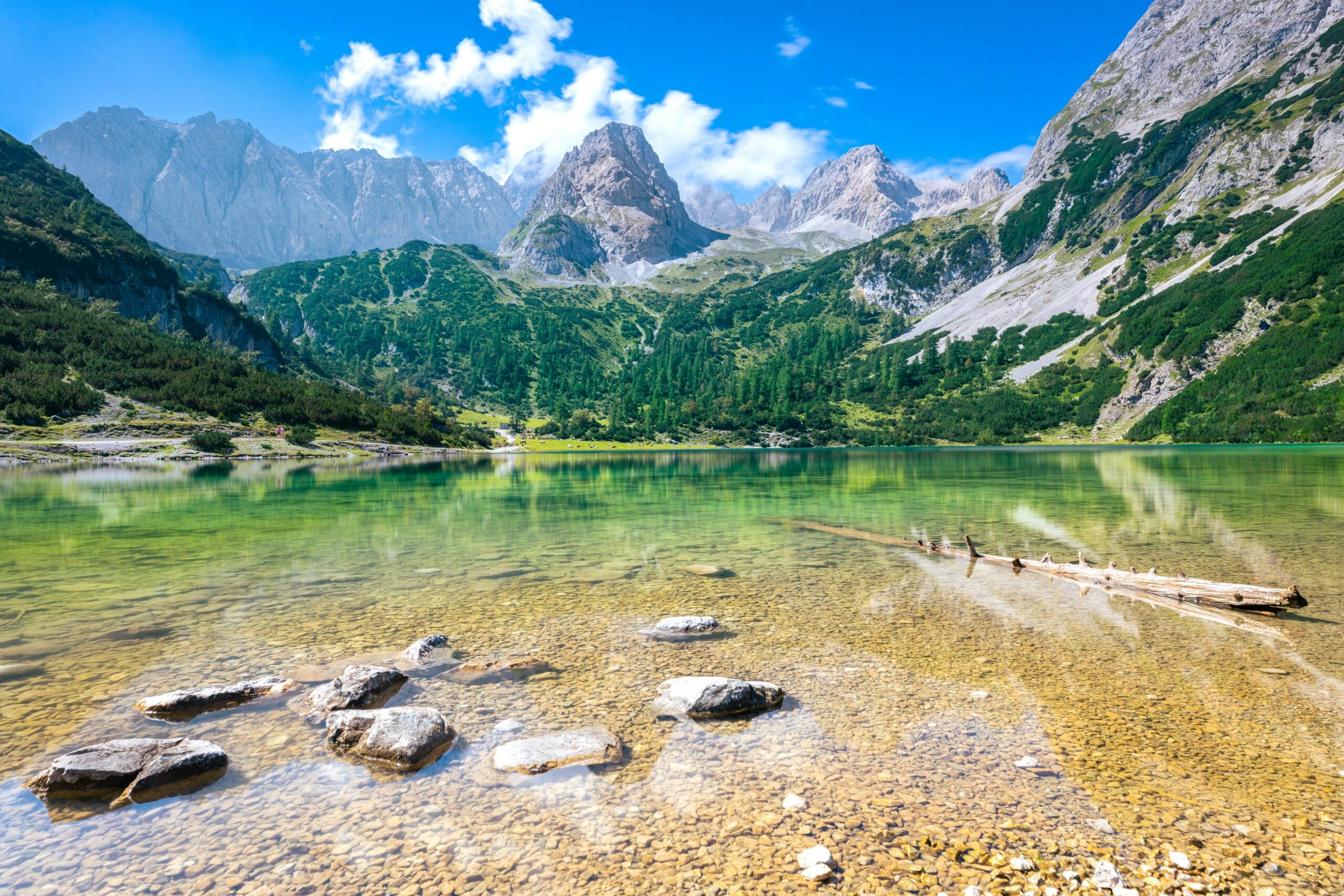Austrijski njemački jezik – tradicionalne drvene kuće u austrijskom alpskom selu okružene zelenim pašnjacima i planinskim vrhovima.