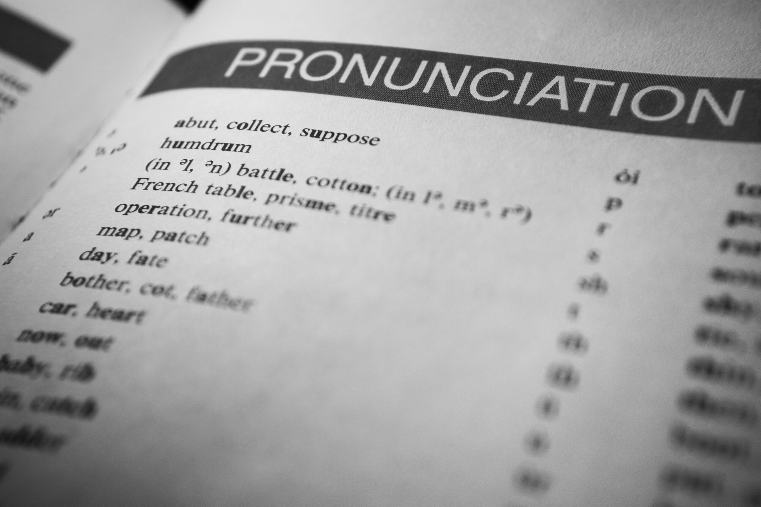 Komplikovane engleske riječi – crno-bijeli krupni plan stranice u rječniku na kojoj je velikim štampanim slovima istaknut naslov poglavlja PRONUNCIATION, uz primjere fonetske transkripcije riječi