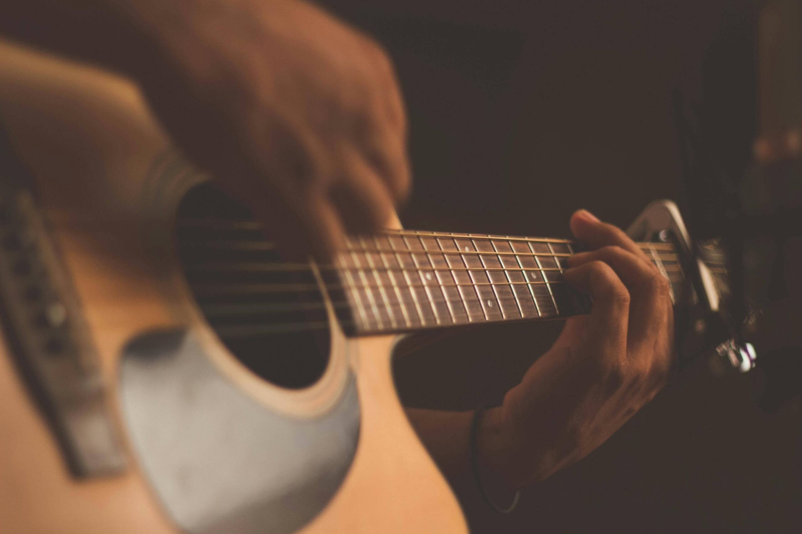 Ruka svira akorde na akustičnoj gitari u muzičkom studiju