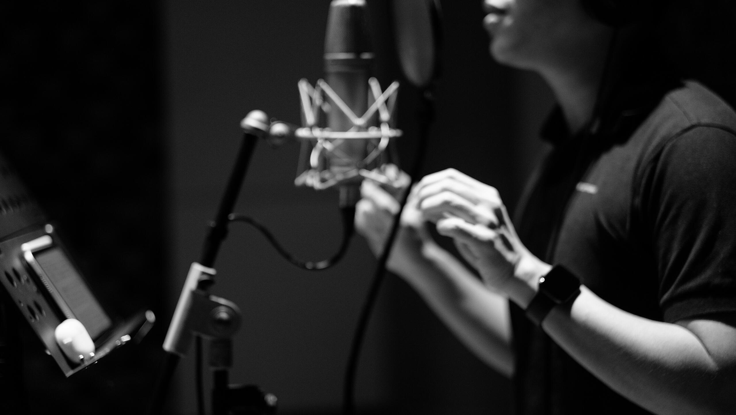 Pjevač sa slušalicama pjeva ispred mikrofona u muzičkom studiju